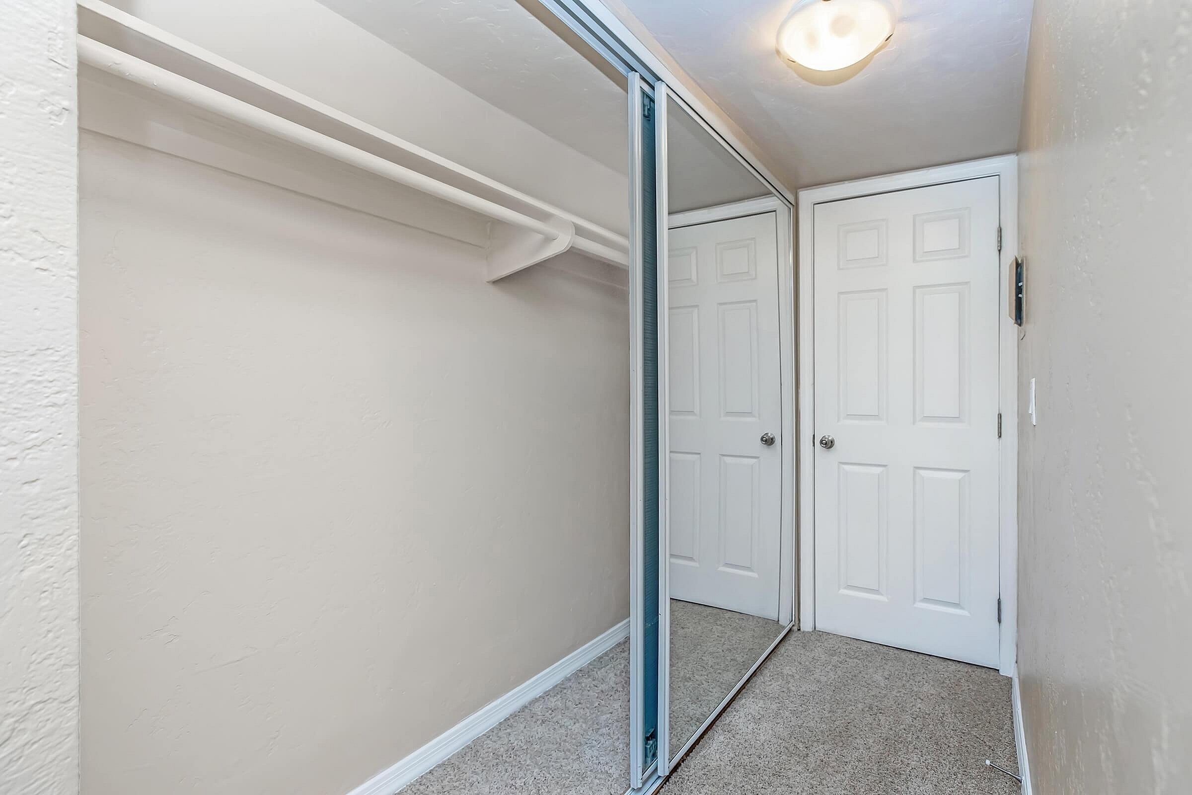 Spacious walk-in closet with elegant mirrored sliding doors and ample storage space.