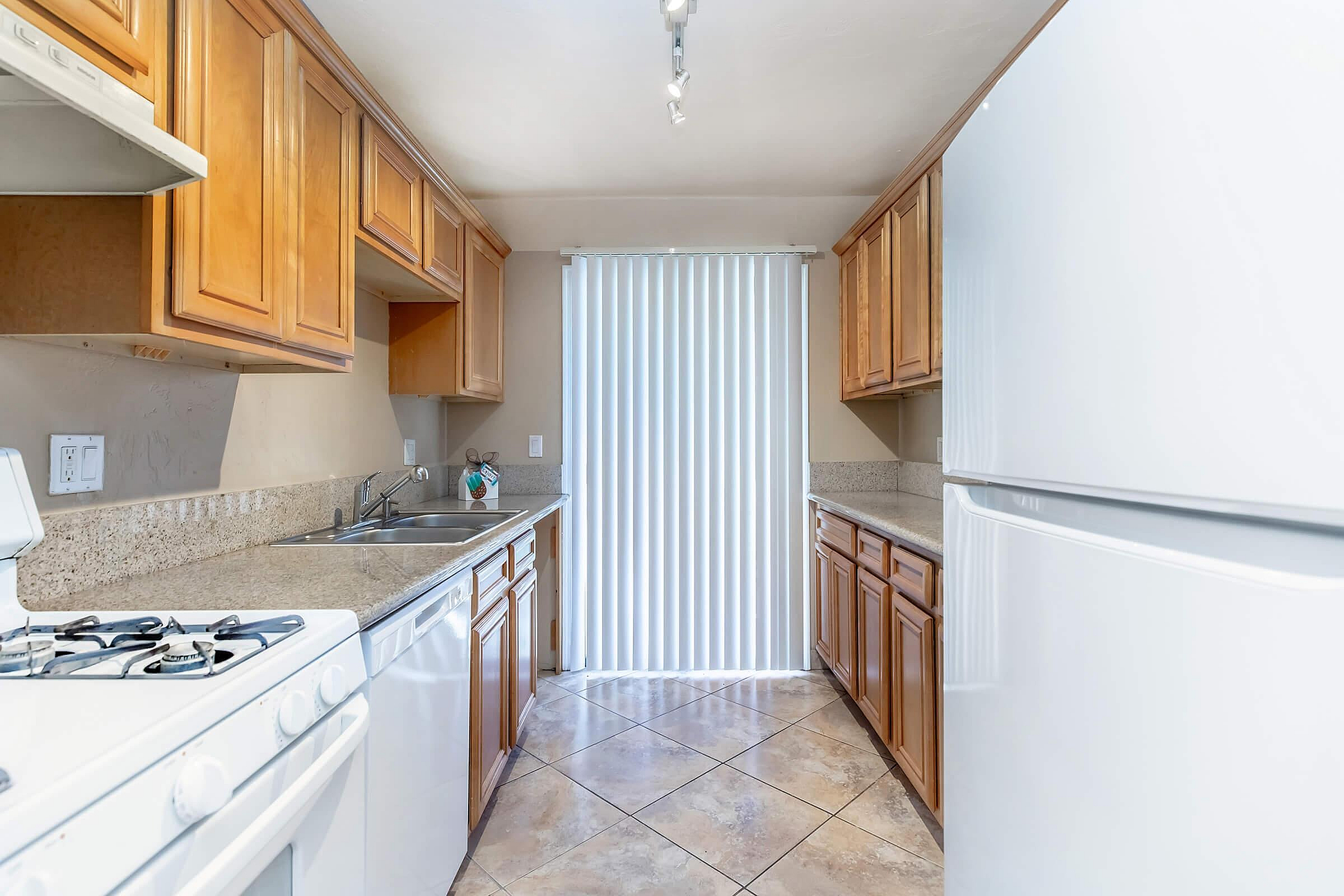 Bright, modern kitchen with sleek granite countertops, wooden cabinets, and elegant tile flooring.