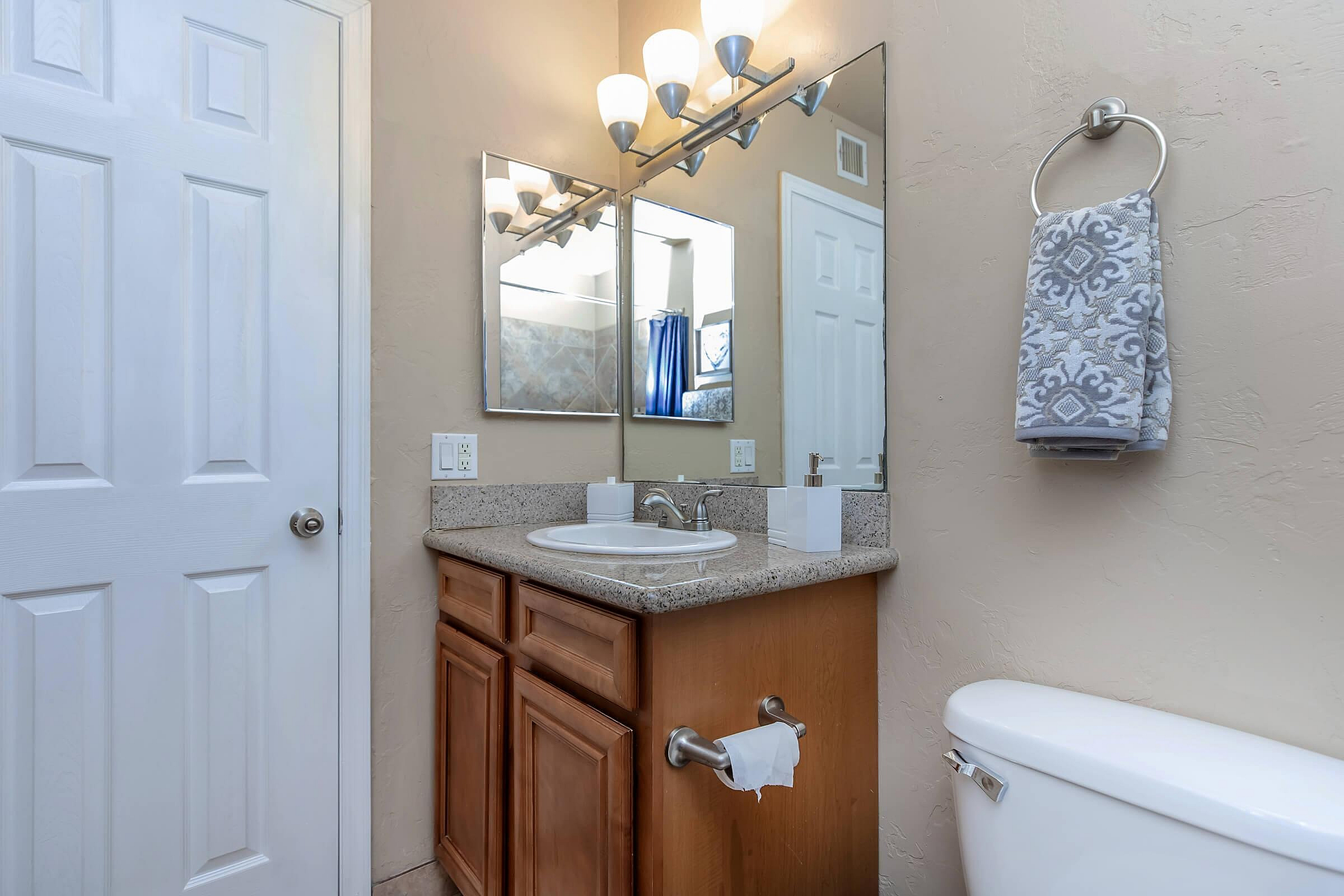 Elegant bathroom featuring a modern vanity with granite countertop, stylish lighting, and a decorative towel ring.