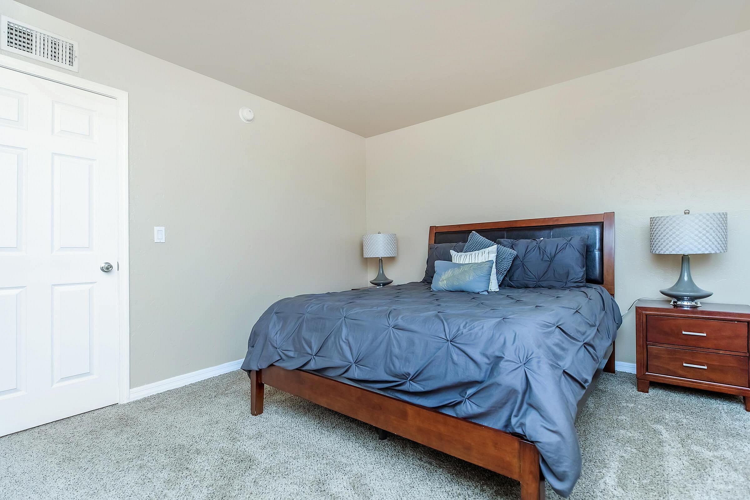 Modern bedroom featuring a stylish wooden bed with elegant gray bedding and cozy lighting.