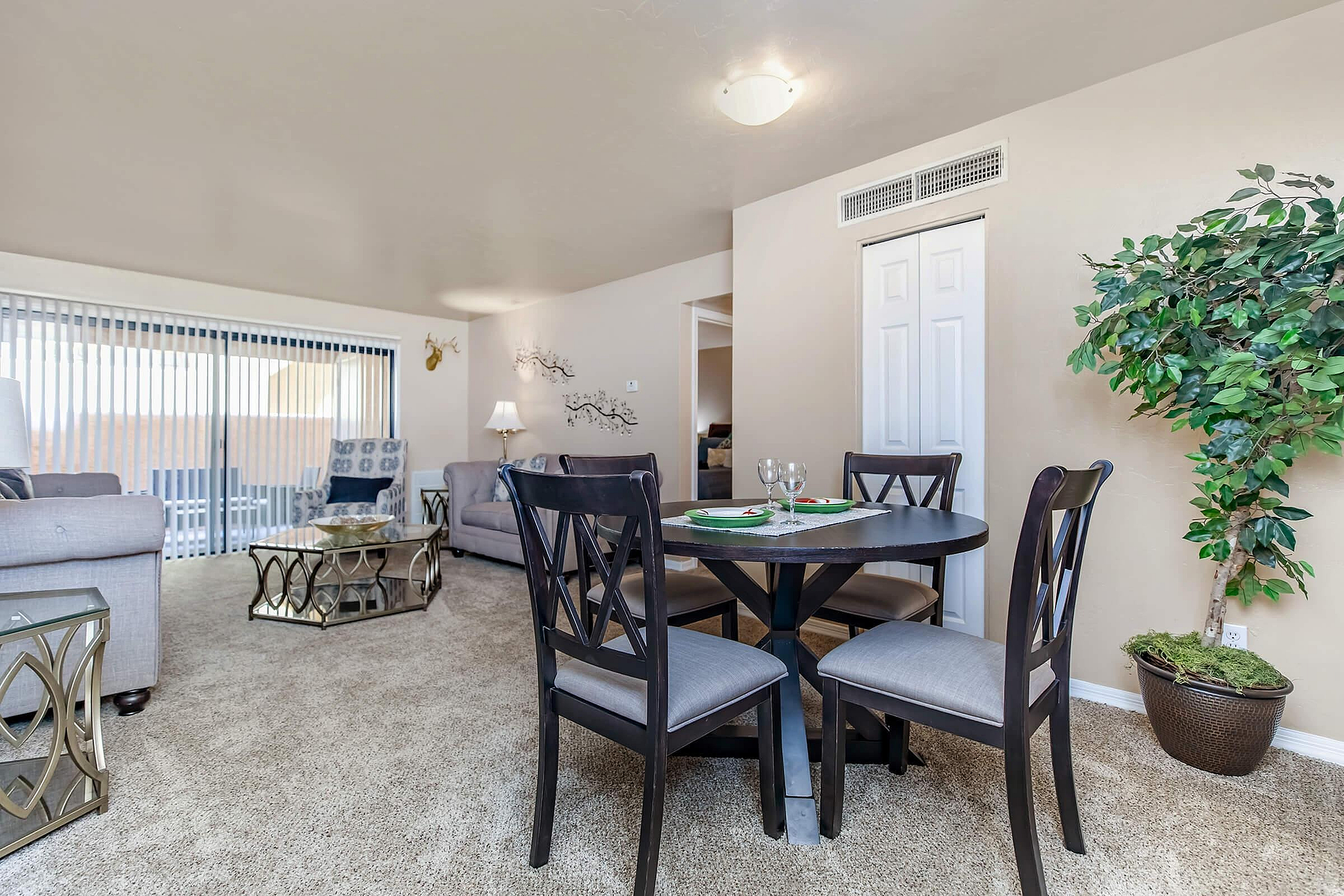 Inviting open-plan living room with plush carpeting, stylish furniture, and natural light streaming through large sliding doors, ideal for relaxation and entertainment.
