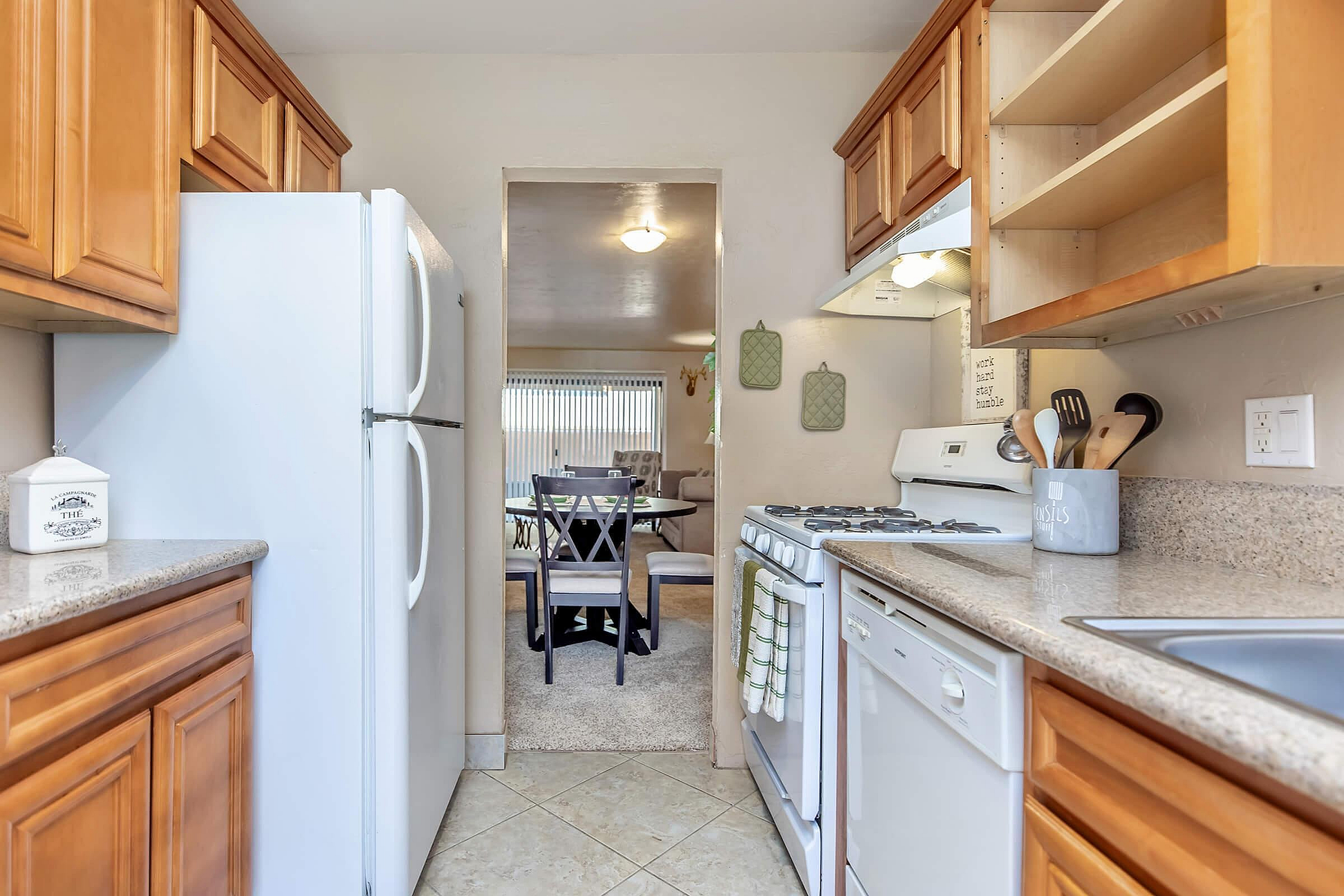Contemporary kitchen with warm wood cabinets, spacious countertops, and a cozy dining area view in the background.