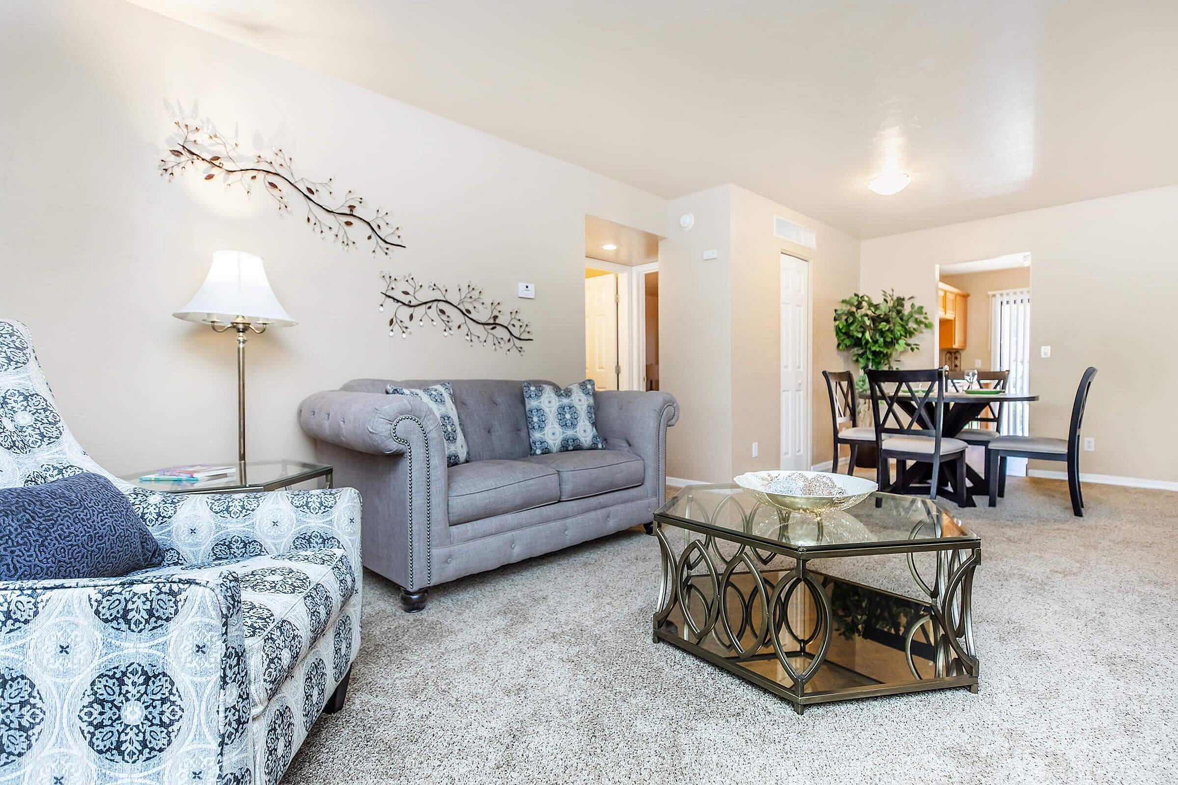 Inviting living room with elegant sofa, modern armchair, stylish décor, and a chic glass coffee table.