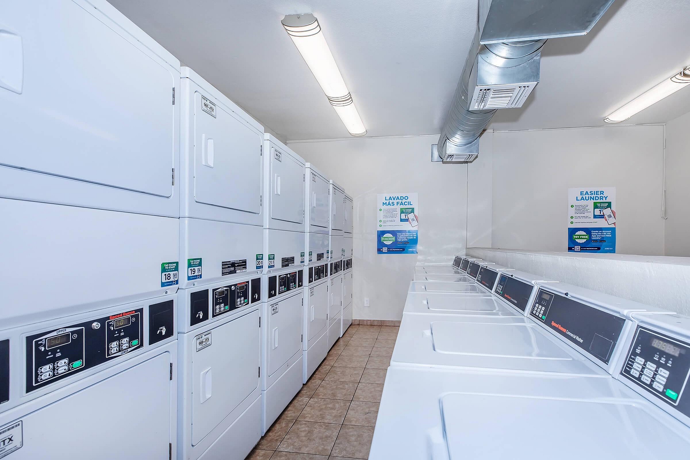 Bright and modern laundry room featuring multiple high-efficiency washers and dryers, perfect for convenient and hassle-free laundry days.