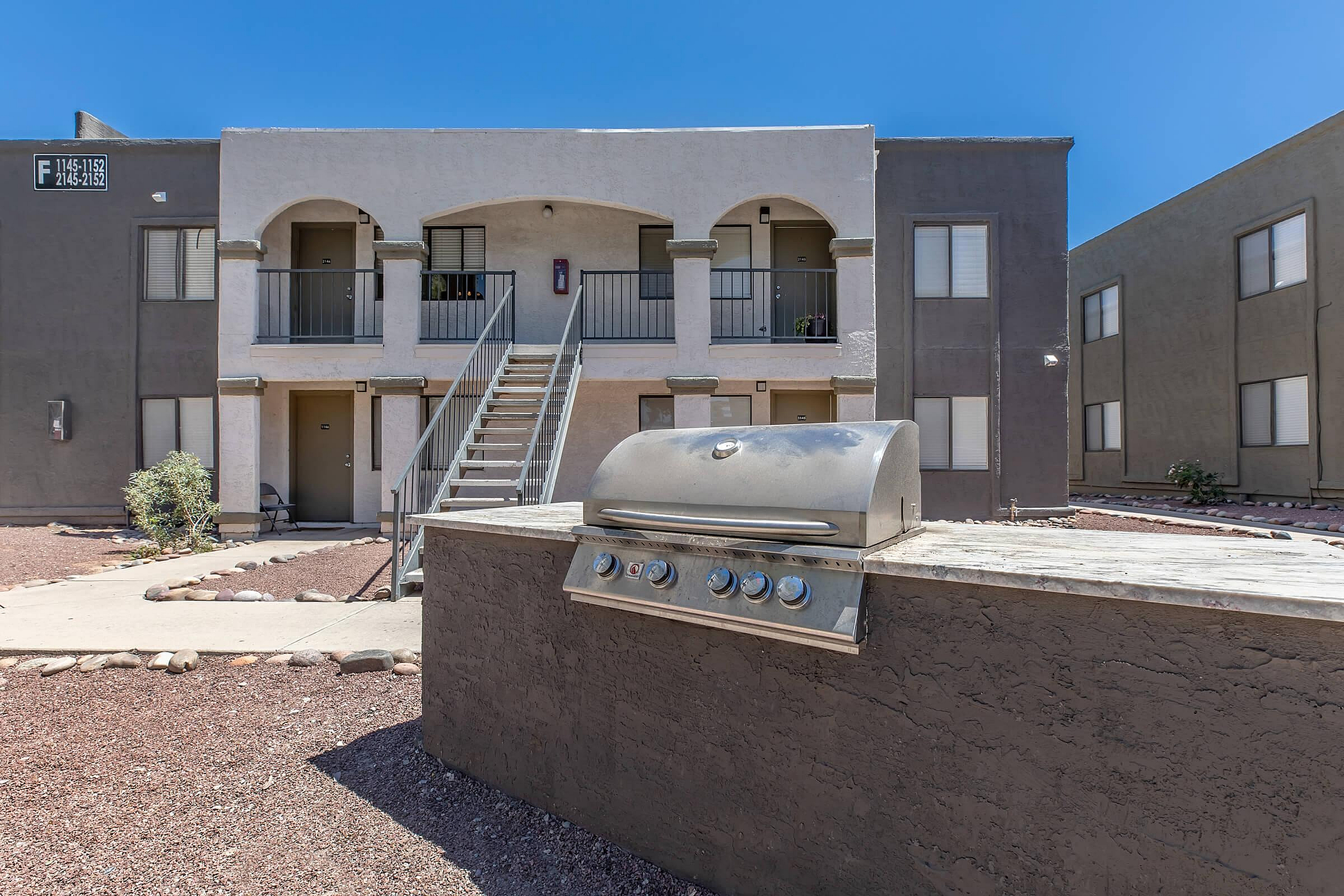Charming modern apartment complex featuring a built-in outdoor grill and inviting two-story arched facade.