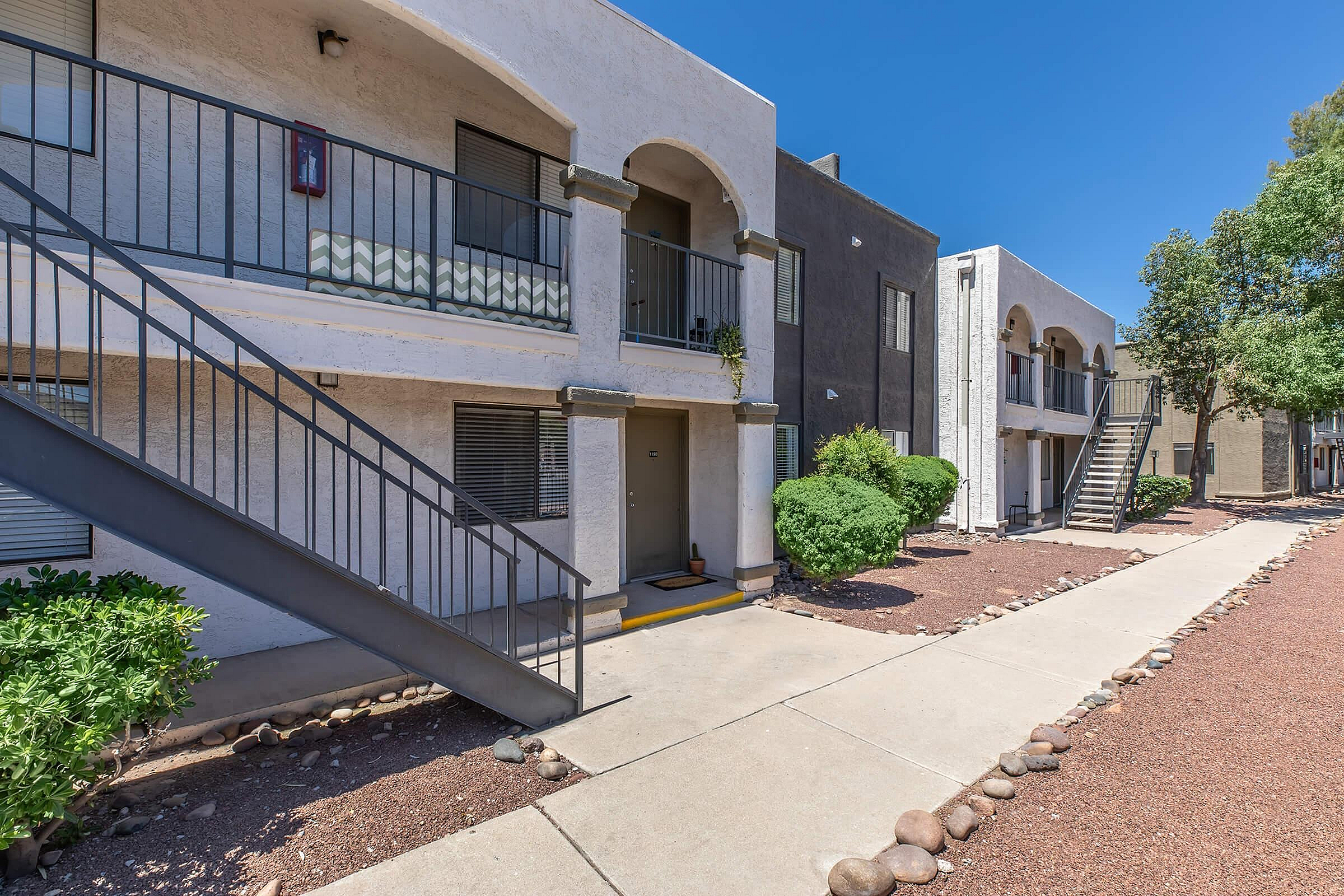 Charming apartment exterior with stylish arches, balcony seating, and lush greenery, ideal for modern living.