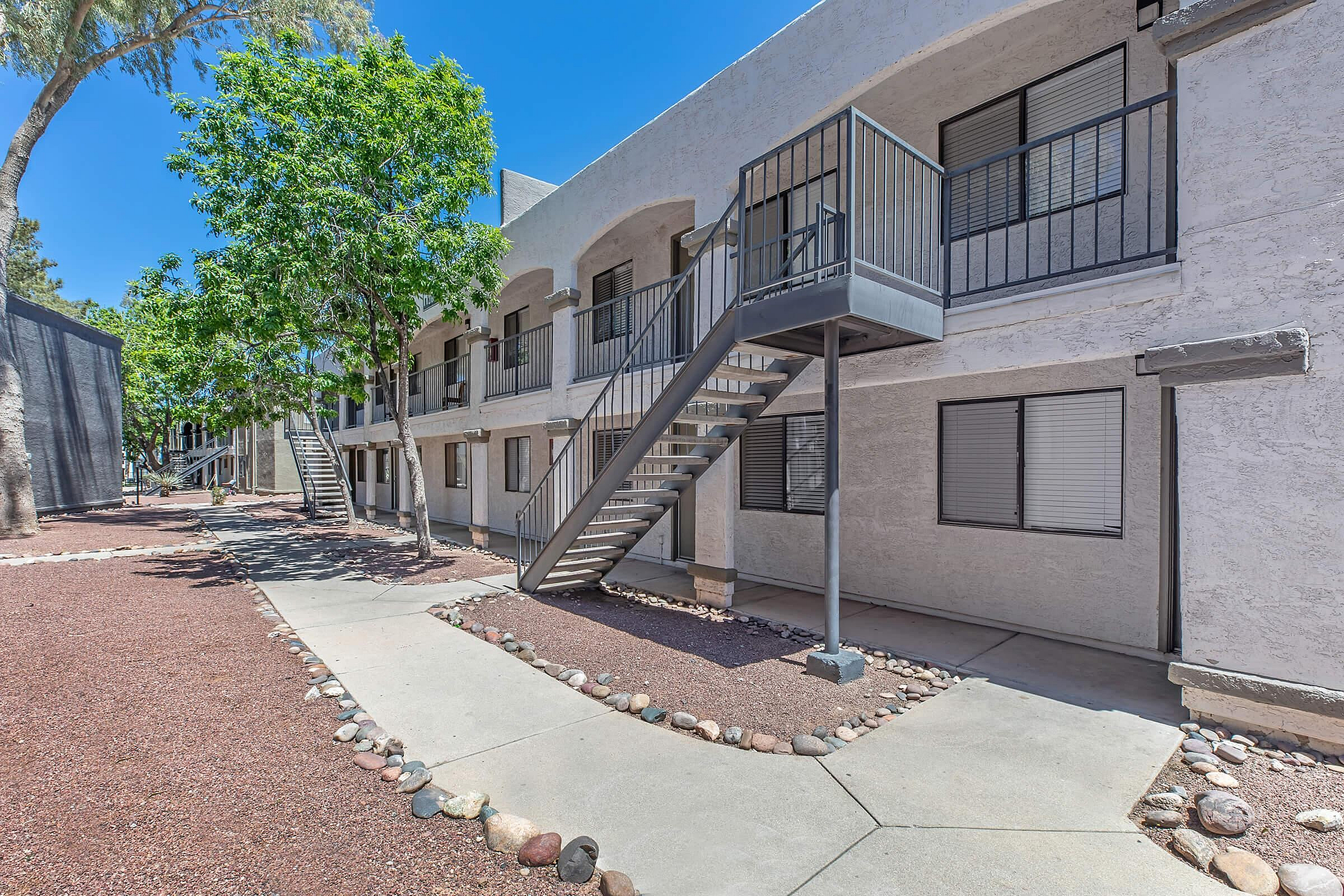 Modern apartment exterior featuring a sleek staircase, lush greenery, and inviting pathways.