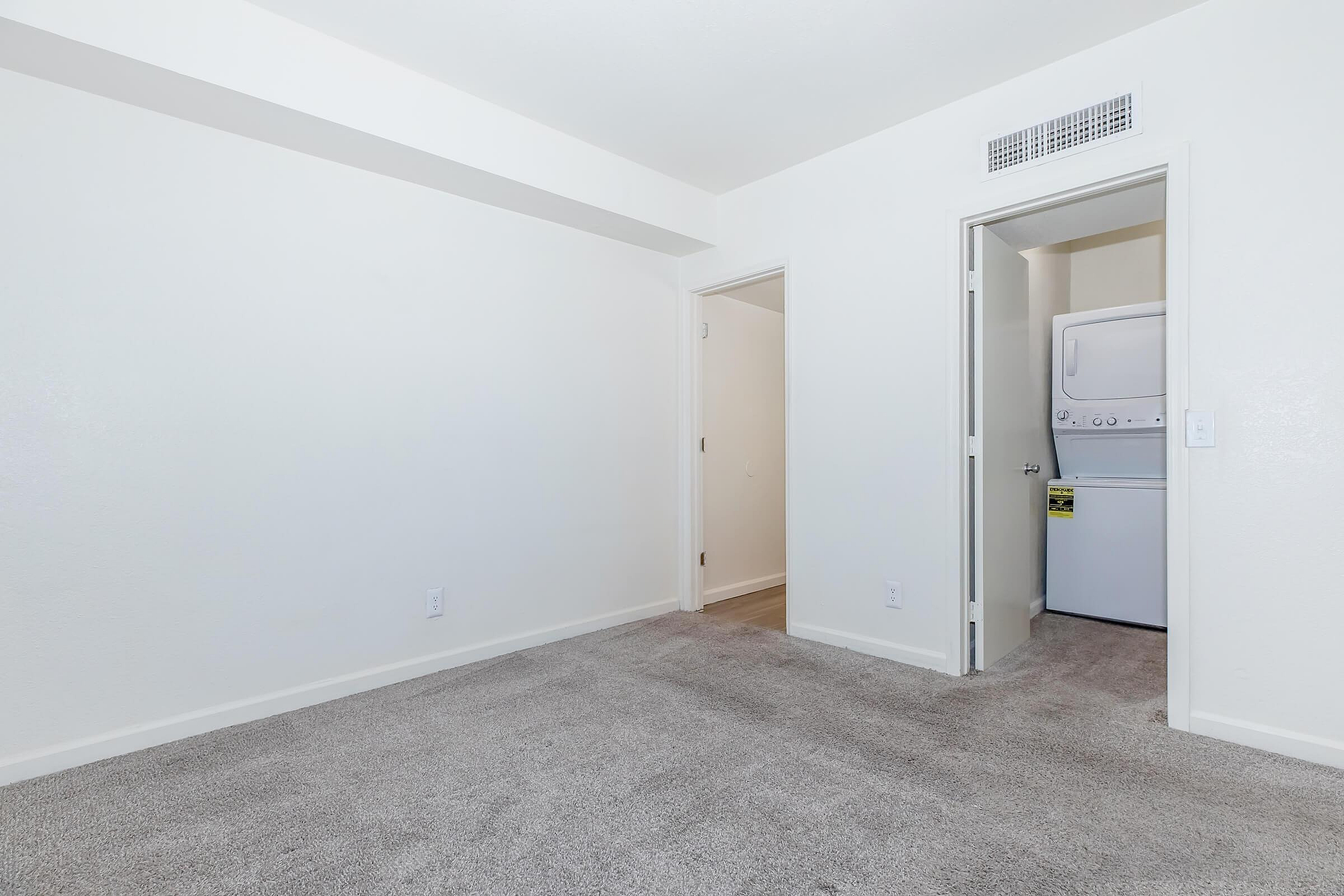 Bright room with plush carpeting and convenient in-unit laundry for modern living.