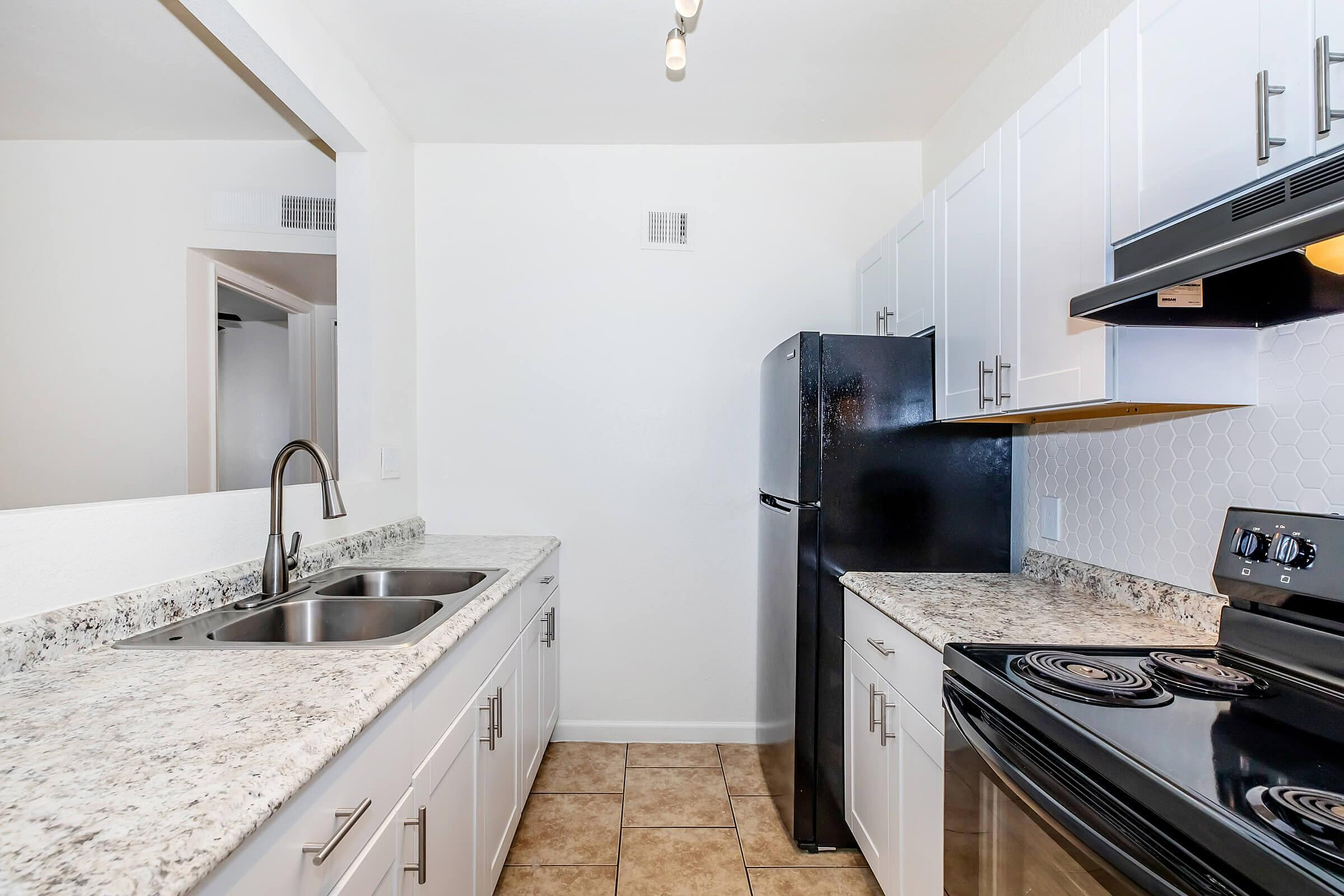 Modern kitchen with elegant granite countertops, sleek black appliances, and stylish white cabinetry, perfect for culinary creativity and social gatherings.