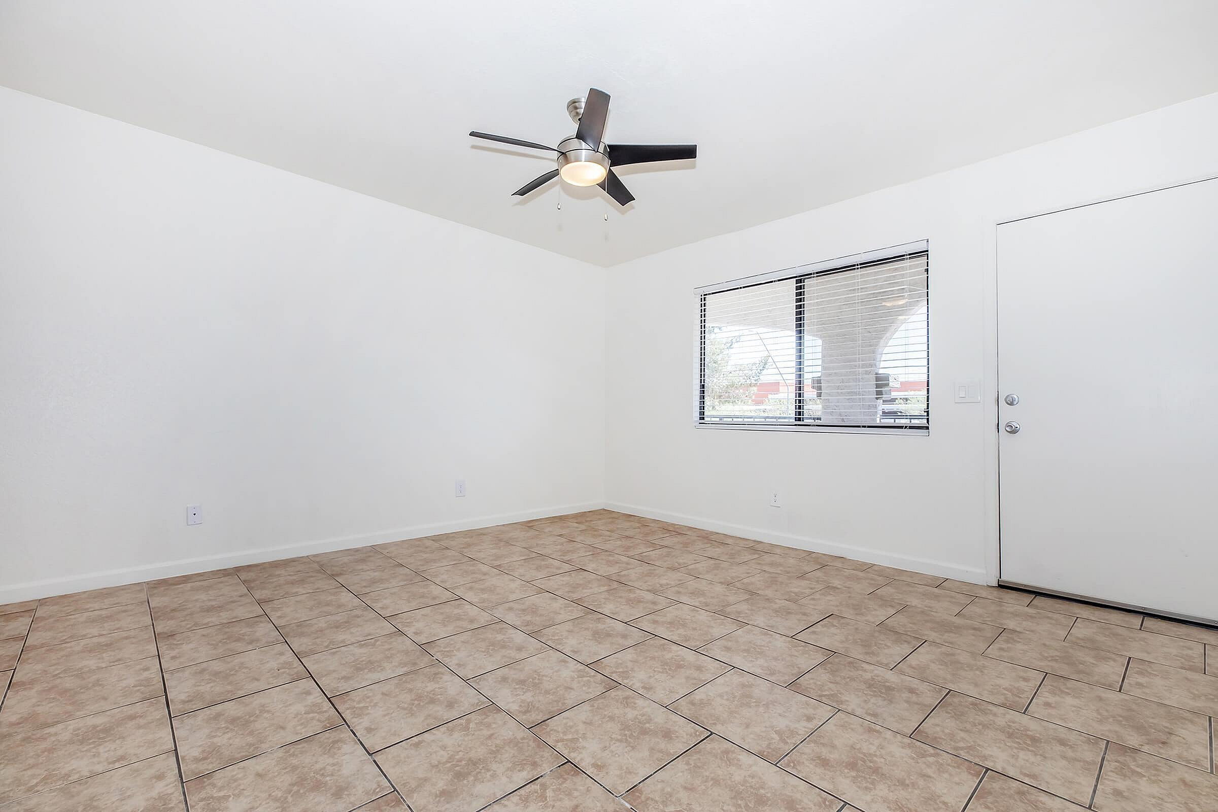 Bright living space with modern ceiling fan, large window, and elegant tiled flooring.