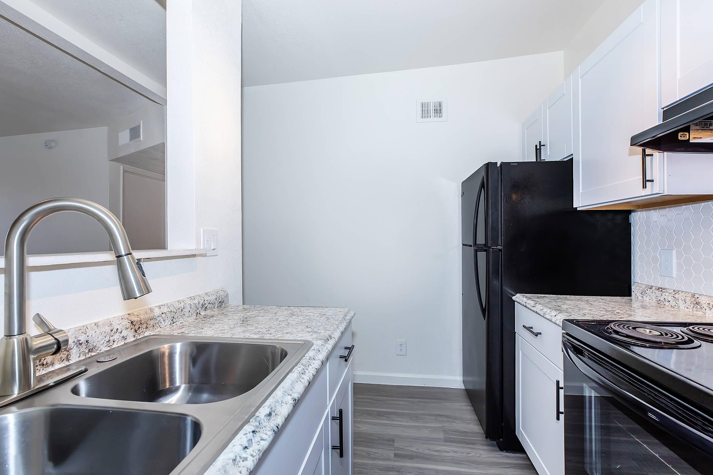Modern kitchen with sleek stainless steel double sink, elegant granite countertops, and stylish white cabinetry.