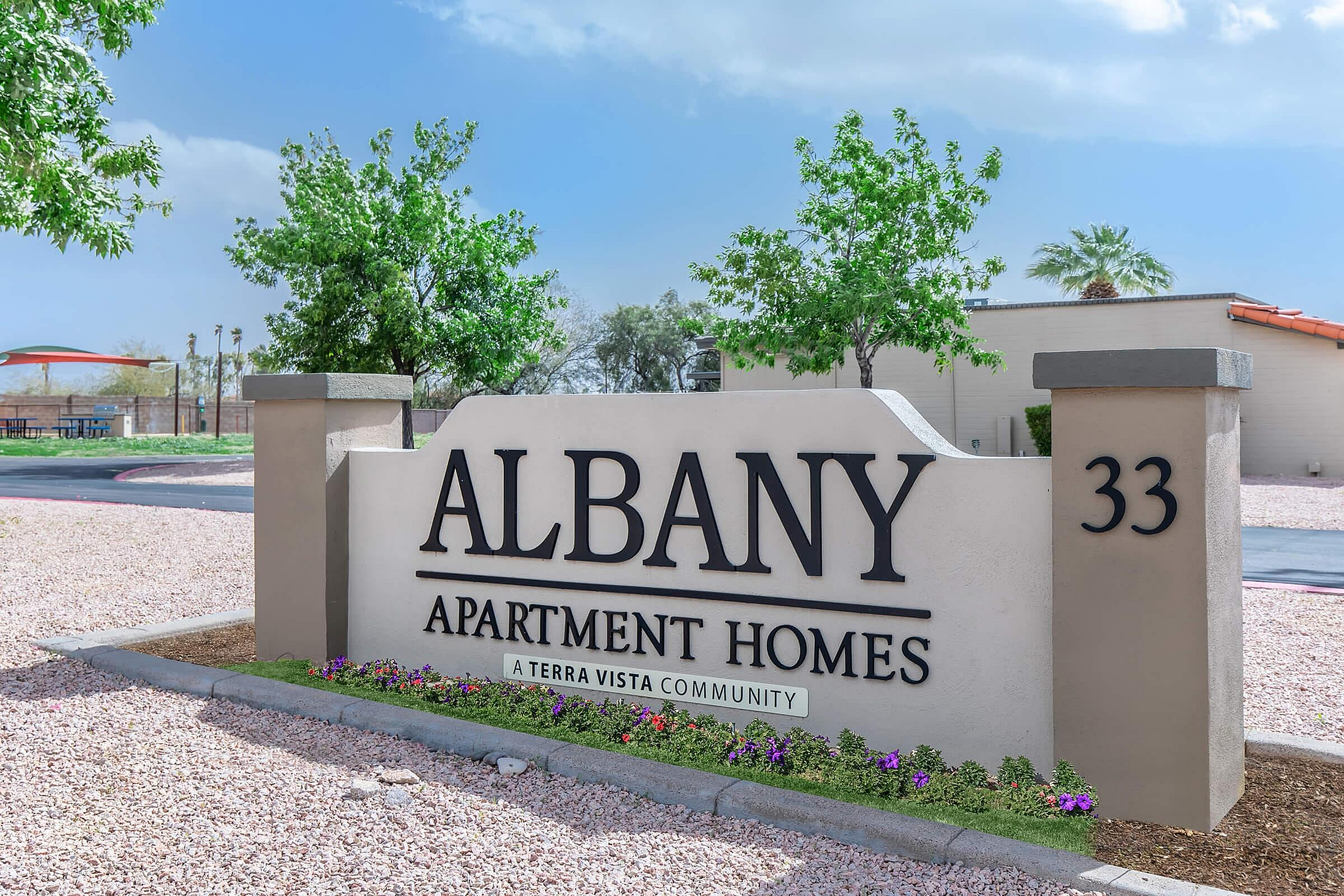 Inviting entrance sign for Albany Apartment Homes in a serene Terra Vista community, surrounded by lush greenery and vibrant flowers.