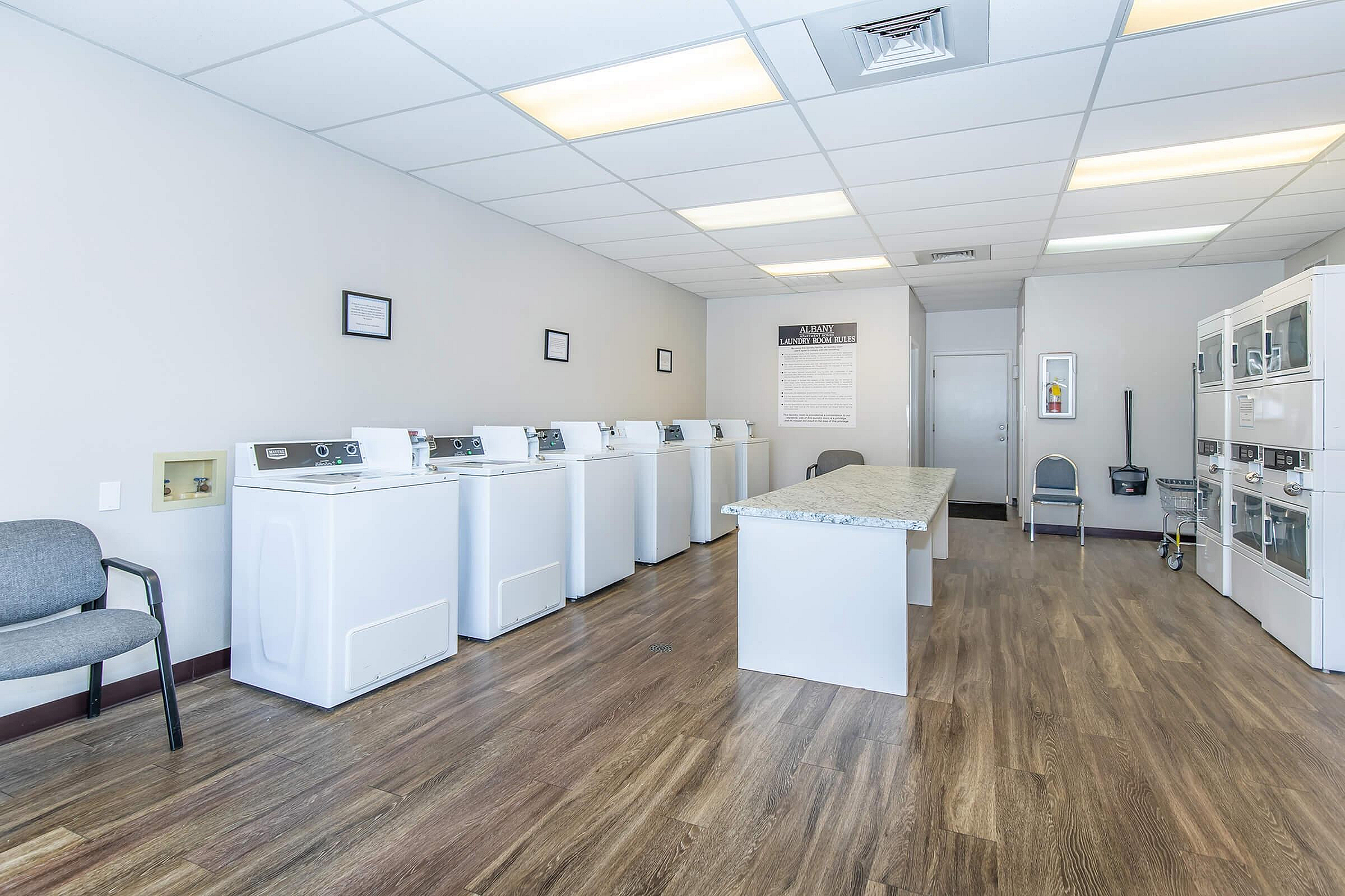 Bright and spacious laundry room with multiple washers and dryers, modern design, and ample seating area.