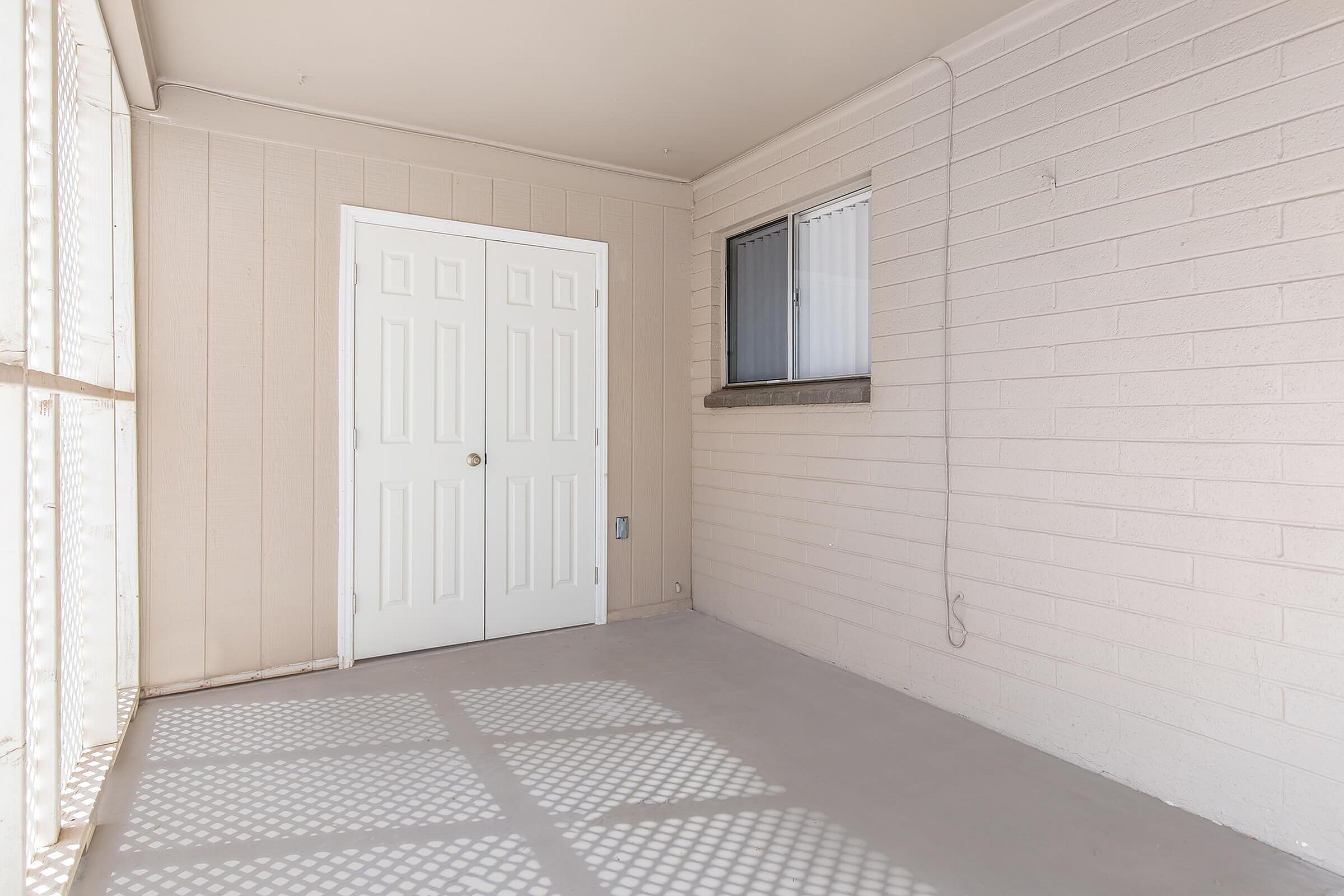 Inviting enclosed patio with sleek double doors and a bright, sunlit ambiance.