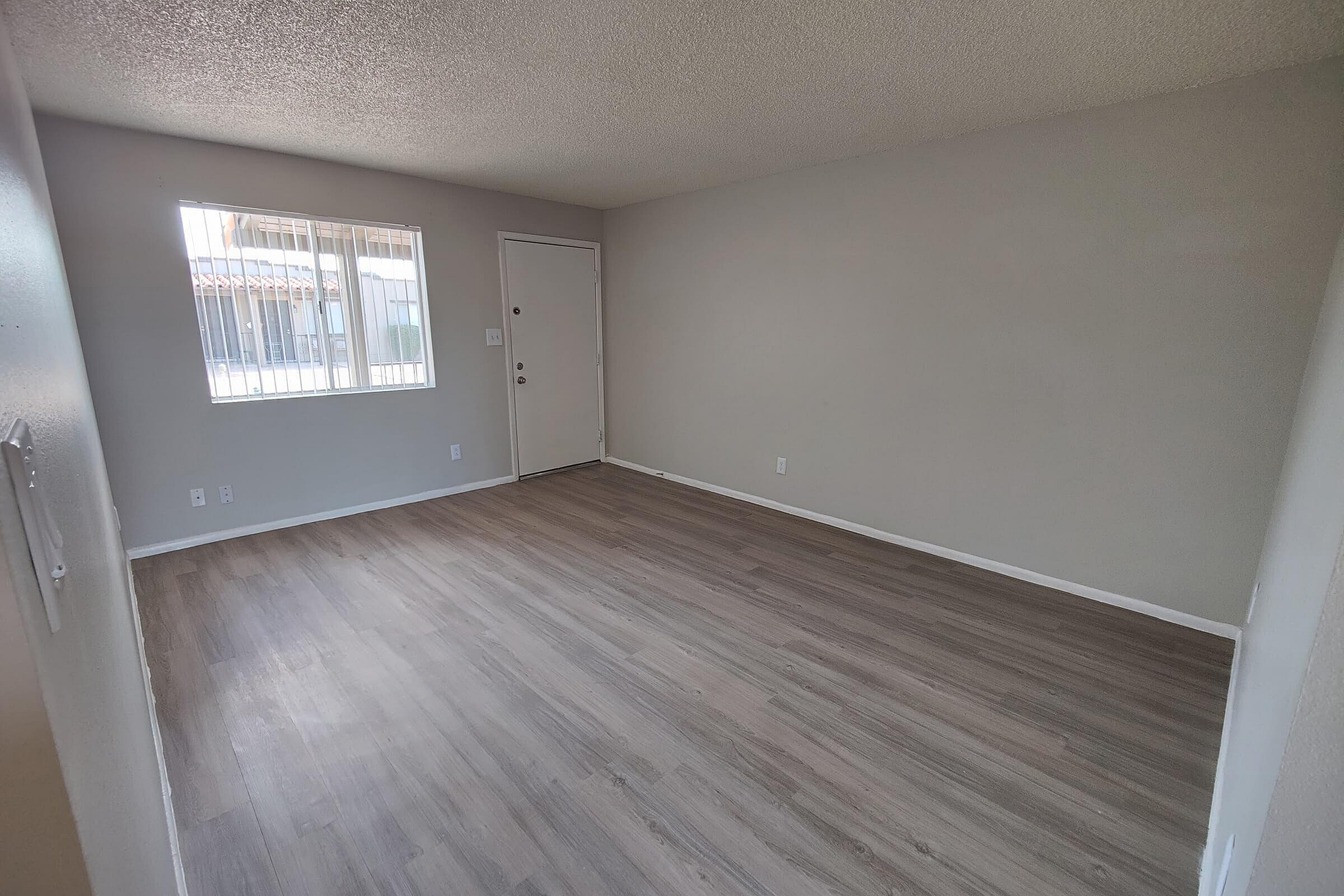 Bright, open living space with sleek wood flooring and abundant natural light from large window.