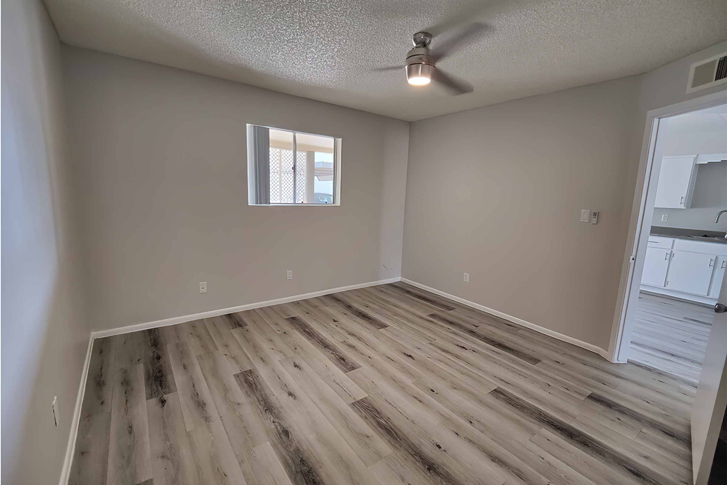 Bright and airy bedroom with elegant wood flooring, modern ceiling fan, and ample natural light.