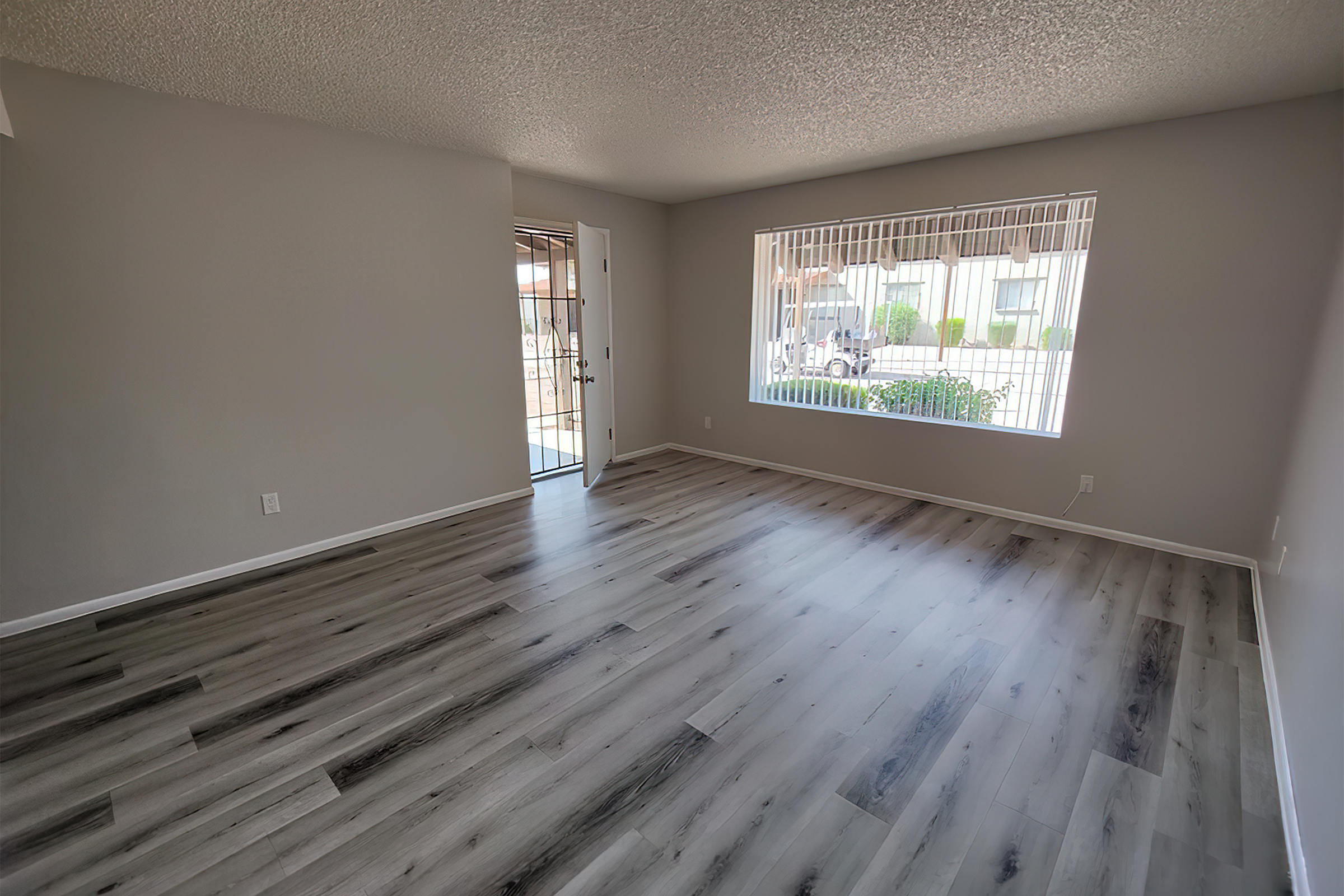 Bright and airy living space with sleek wood flooring and a large window offering natural light.