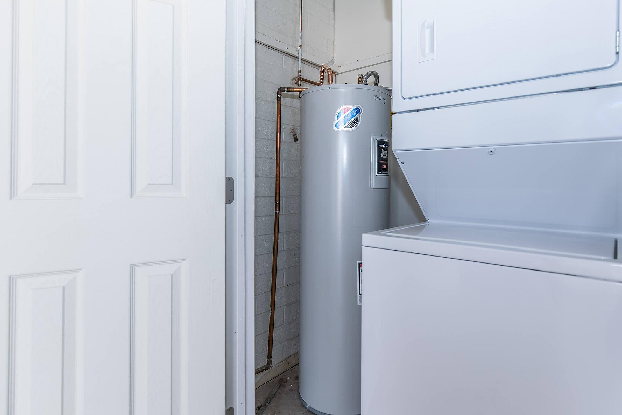 Compact utility area featuring a sleek water heater and convenient stacked washer and dryer.