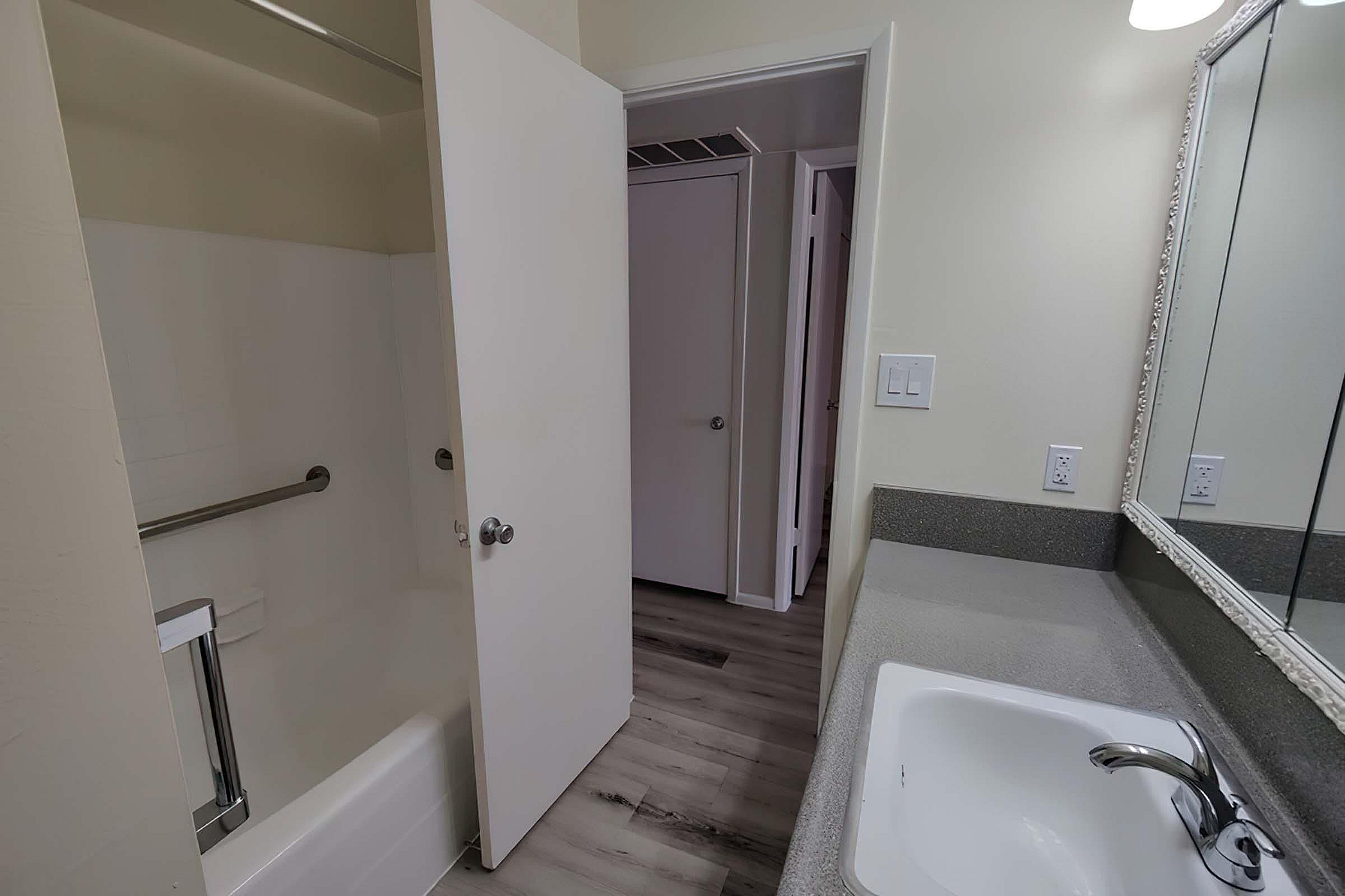 Elegant bathroom featuring a modern sink, spacious countertop, and pristine white bathtub with a convenient shower door.