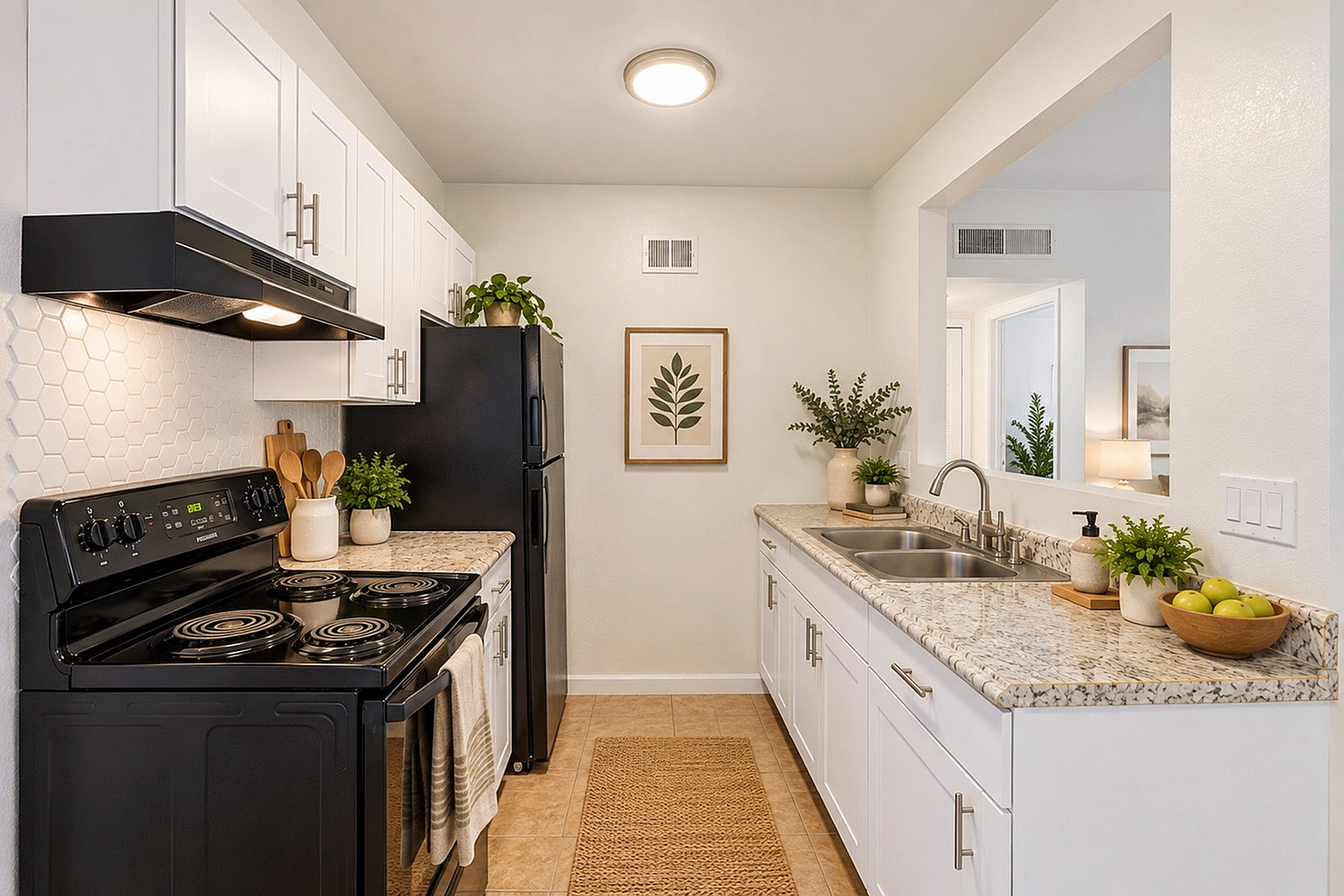 Charming kitchen with modern black appliances, elegant white cabinetry, and granite countertops accentuated by lush green plants and stylish decor.