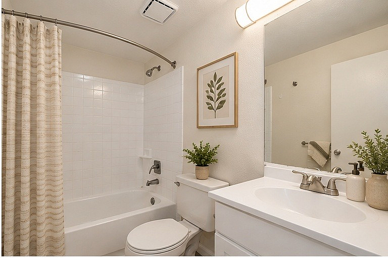 Elegant bathroom featuring a sleek white bathtub, contemporary fixtures, and stylish decor with a leafy wall art accent.