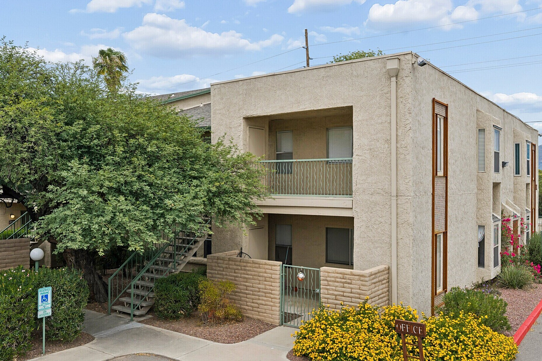 Charming apartment with a classic two-story facade, surrounded by vibrant greenery and blooming flowers, offering scenic views and easy accessibility.