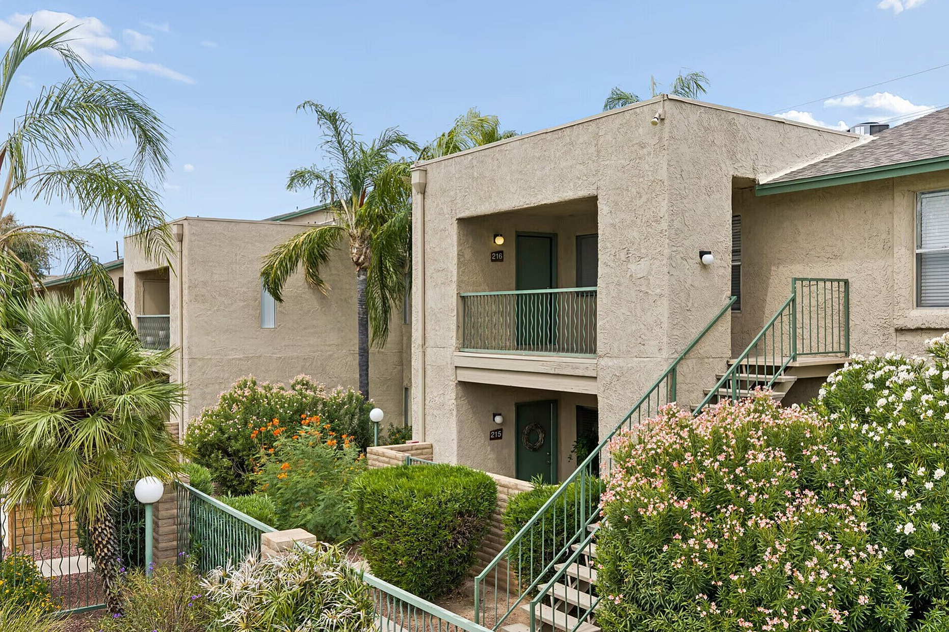 Charming apartment complex with lush greenery and palm trees, offering a tranquil living environment.