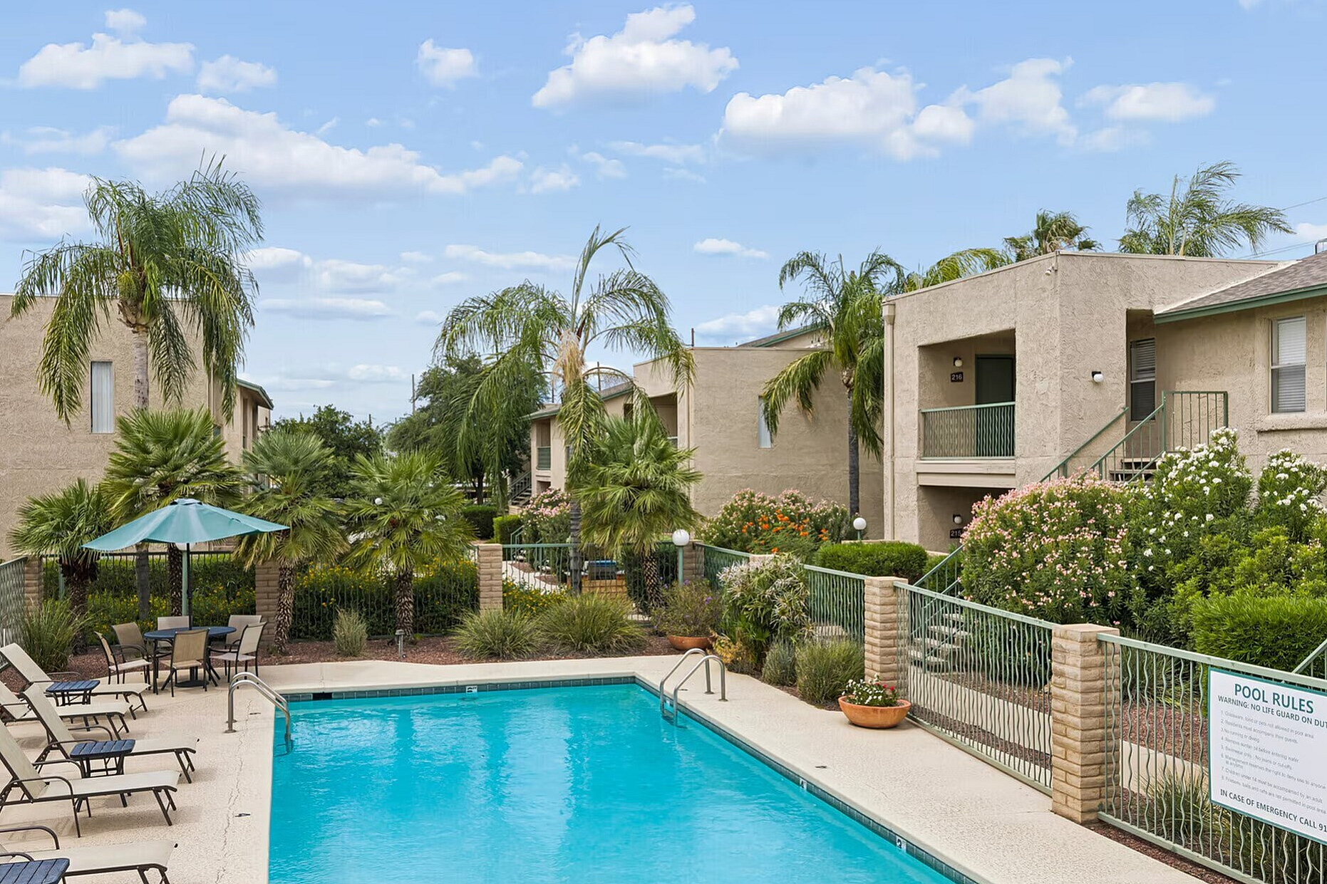 Inviting apartment complex with lush palm trees and a sparkling pool, perfect for relaxation and leisure.