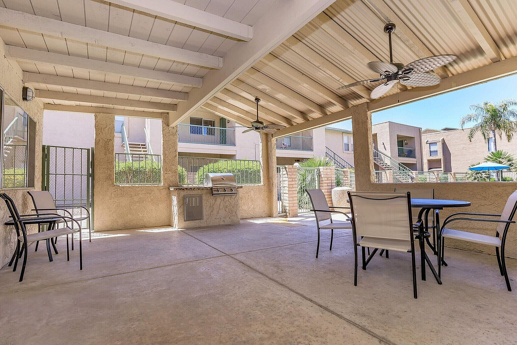 Charming outdoor patio area with ceiling fans, a built-in grill, and elegant seating, perfect for relaxation and entertaining.