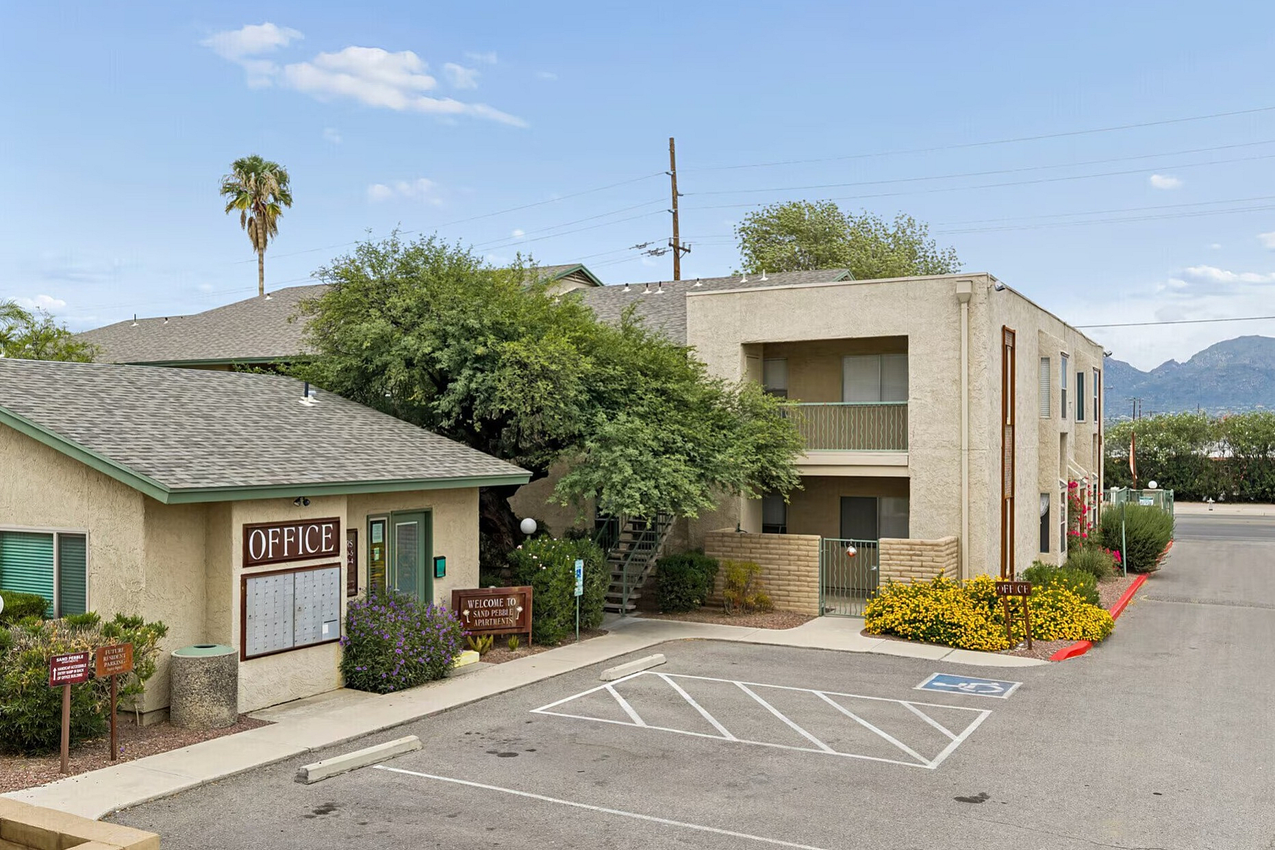 Charming apartment complex with lush greenery, offering a welcoming office entrance and convenient parking.