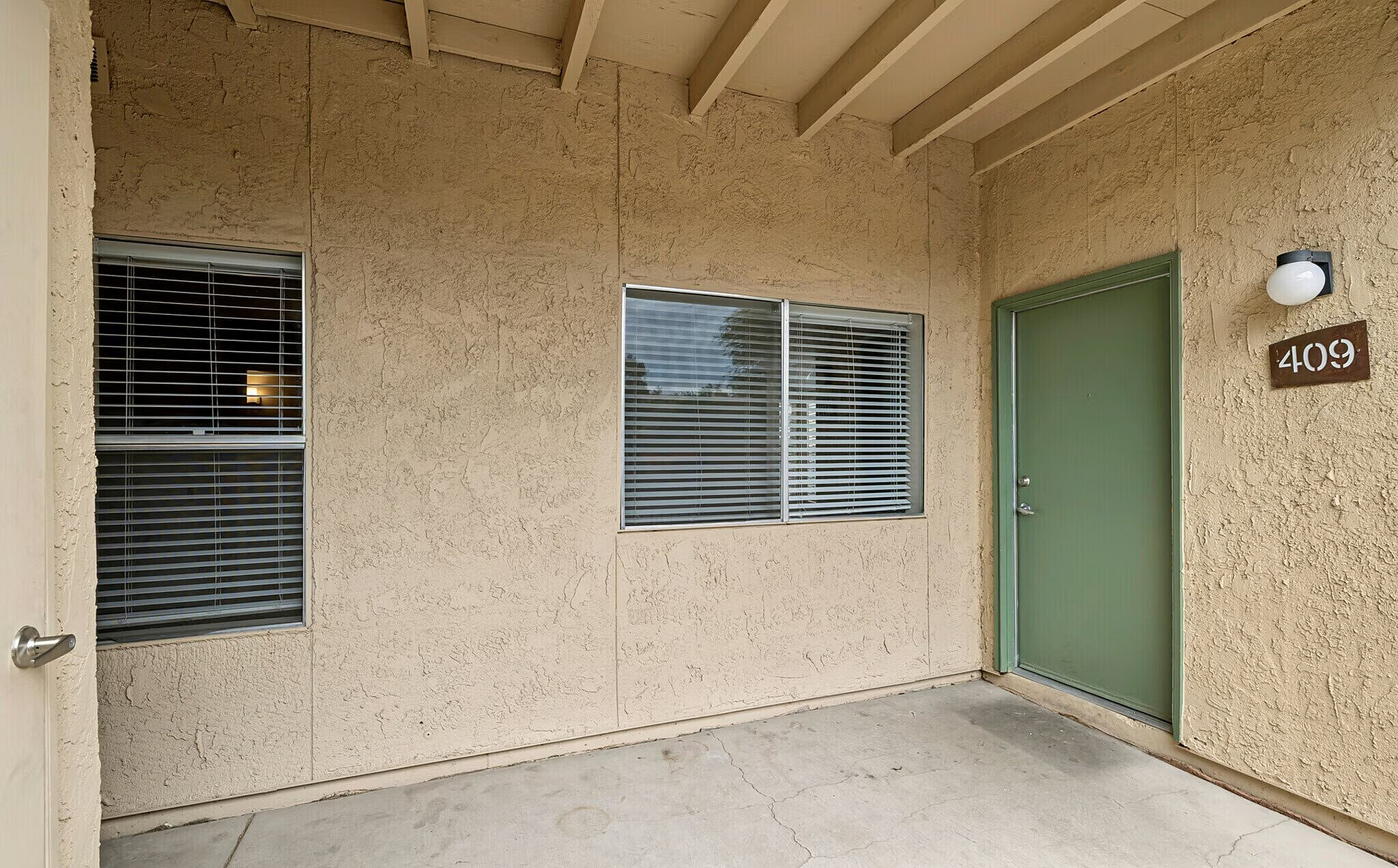 Charming apartment entryway with textured walls, large window, and stylish green door.