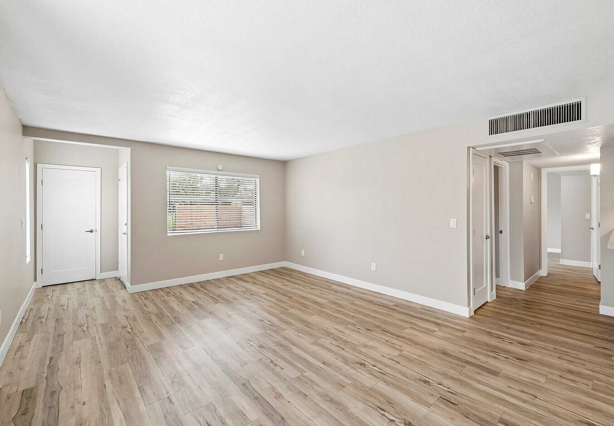 Bright and spacious living area featuring elegant wood flooring, large windows, and neutral walls, offering a modern and inviting atmosphere.