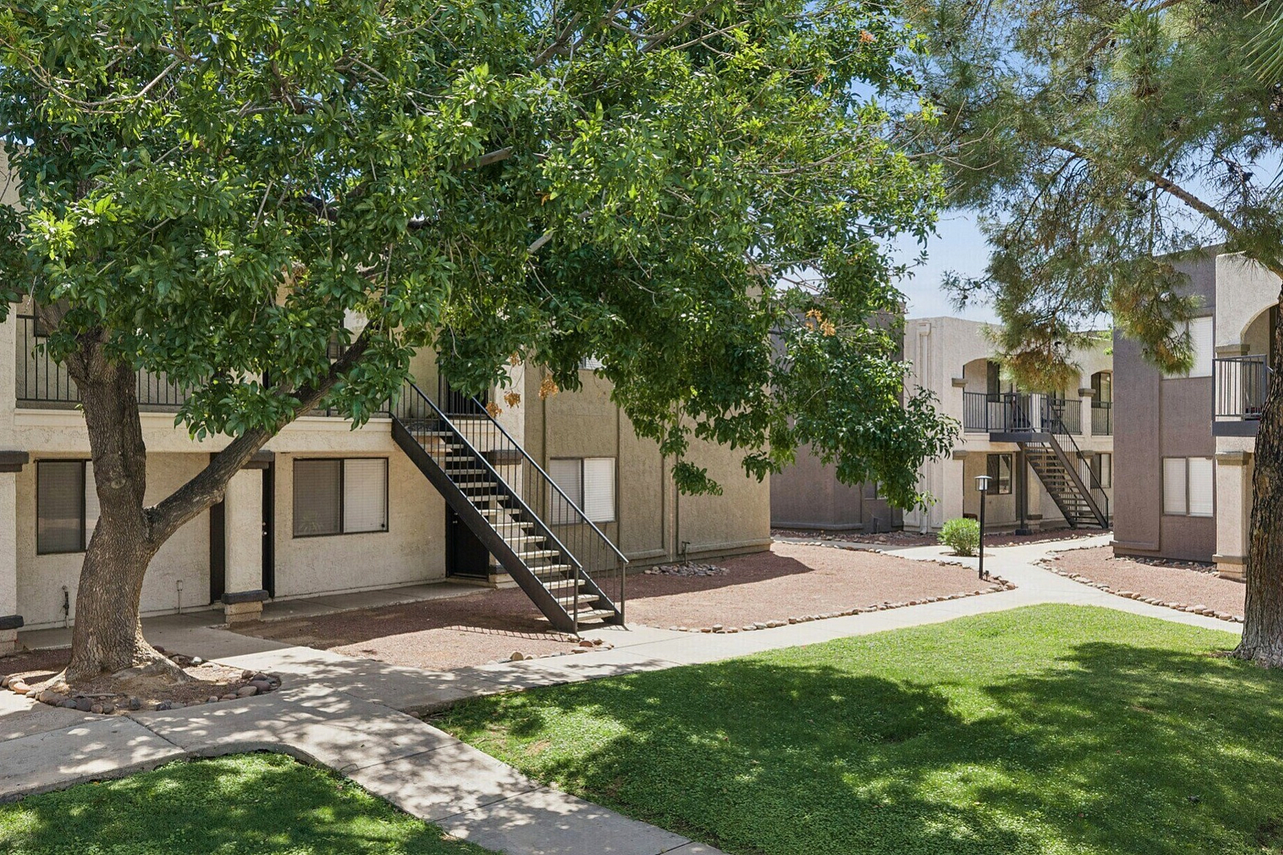 Charming apartment complex surrounded by lush greenery and shaded pathways for a serene living experience.