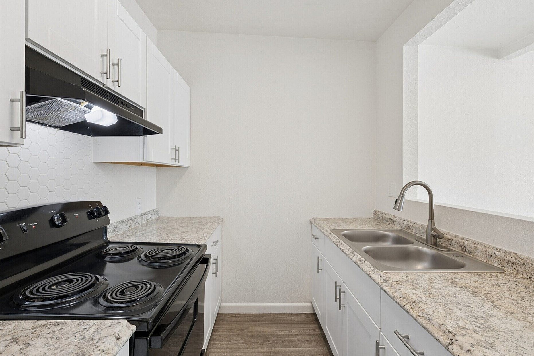Modern kitchen with sleek white cabinetry, elegant countertops, and stainless steel appliances, including a stylish range and double sink.