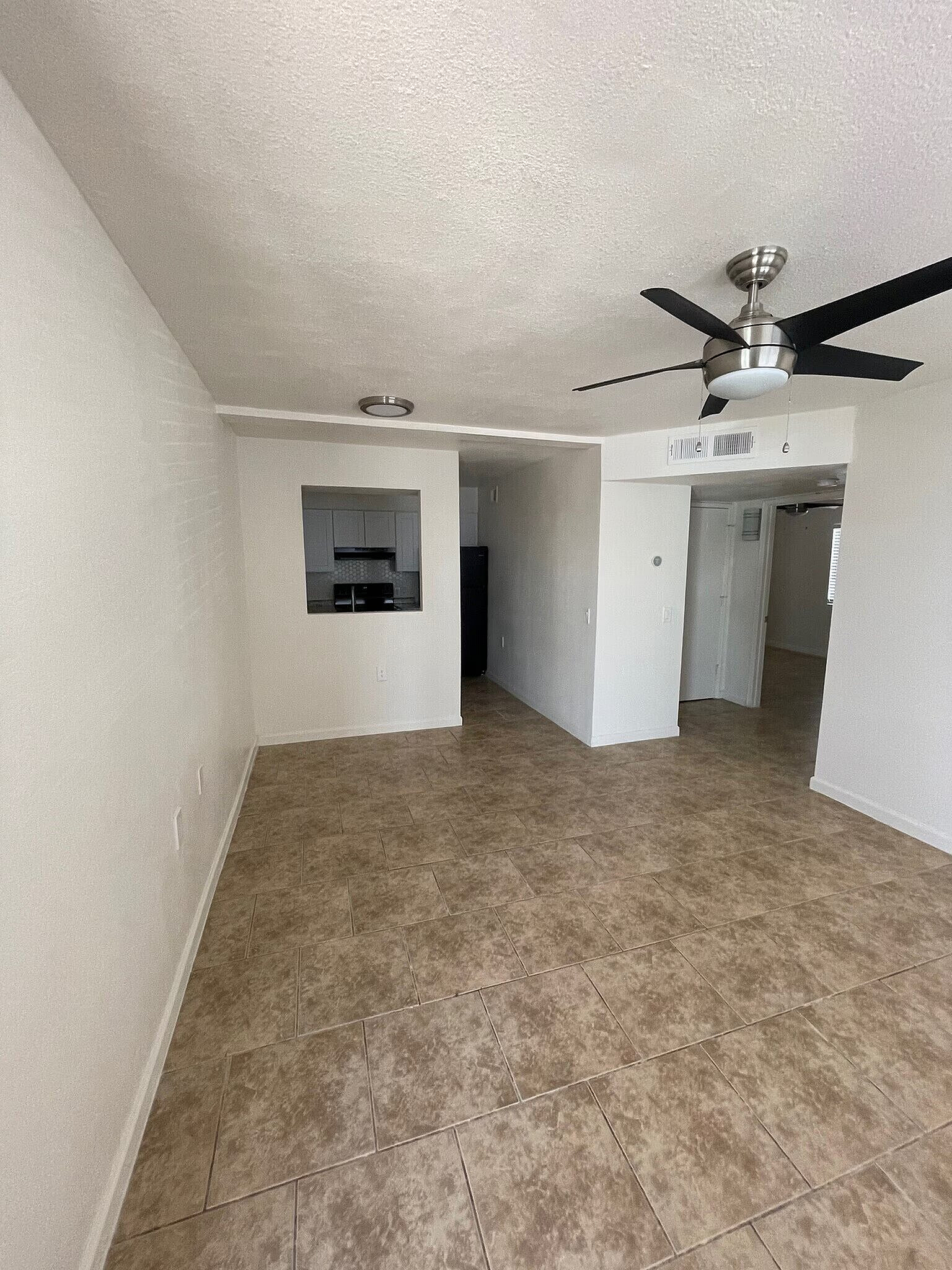 Spacious open-concept living area with elegant tiled flooring and modern ceiling fan, perfect for comfortable living and entertaining.
