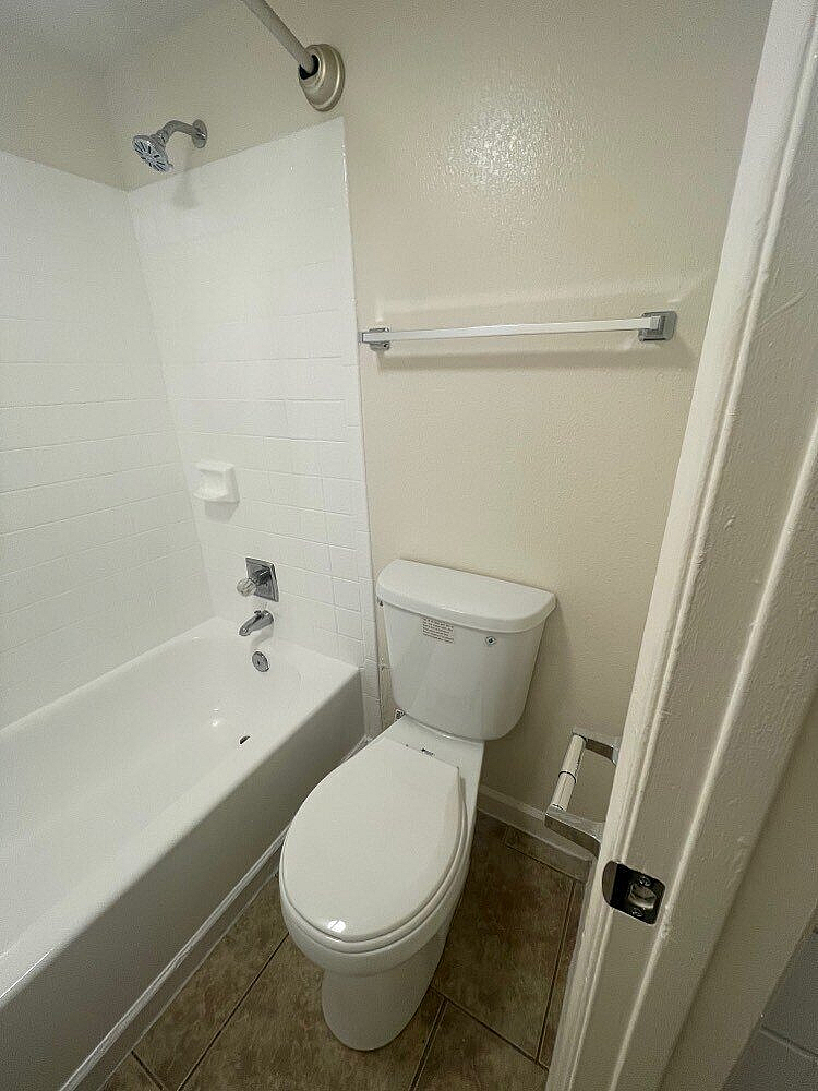 Modern bathroom with elegant tile flooring, featuring a pristine bathtub and sleek toilet for a refreshing experience.
