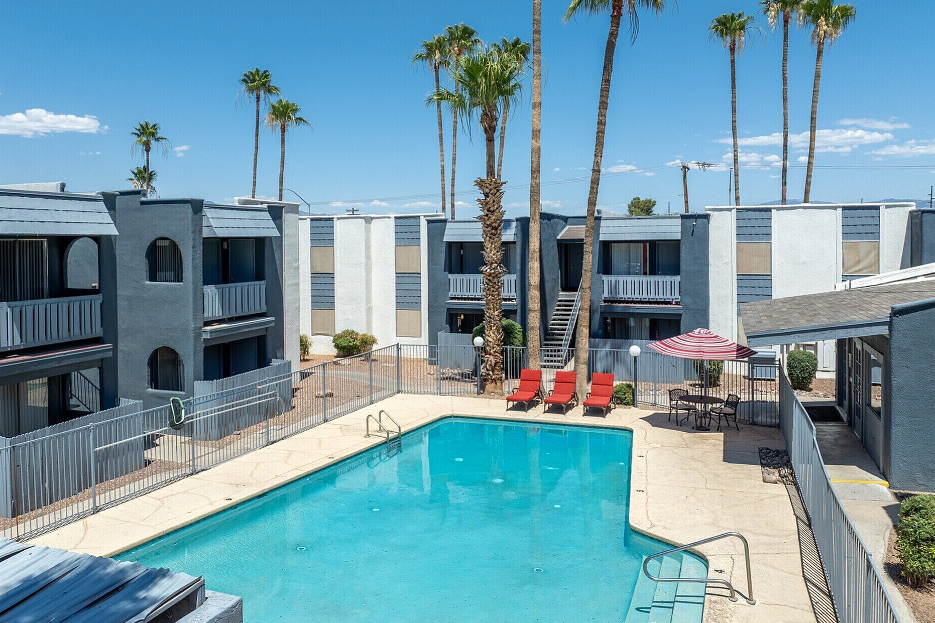 Charming apartment complex with a sparkling swimming pool, surrounded by palm trees and modern architecture, perfect for relaxation and leisure.