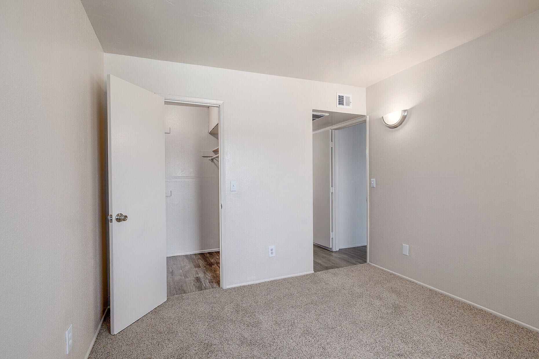 Inviting bedroom with plush carpet, walk-in closet, and soft wall lighting, offering a cozy and functional living space.