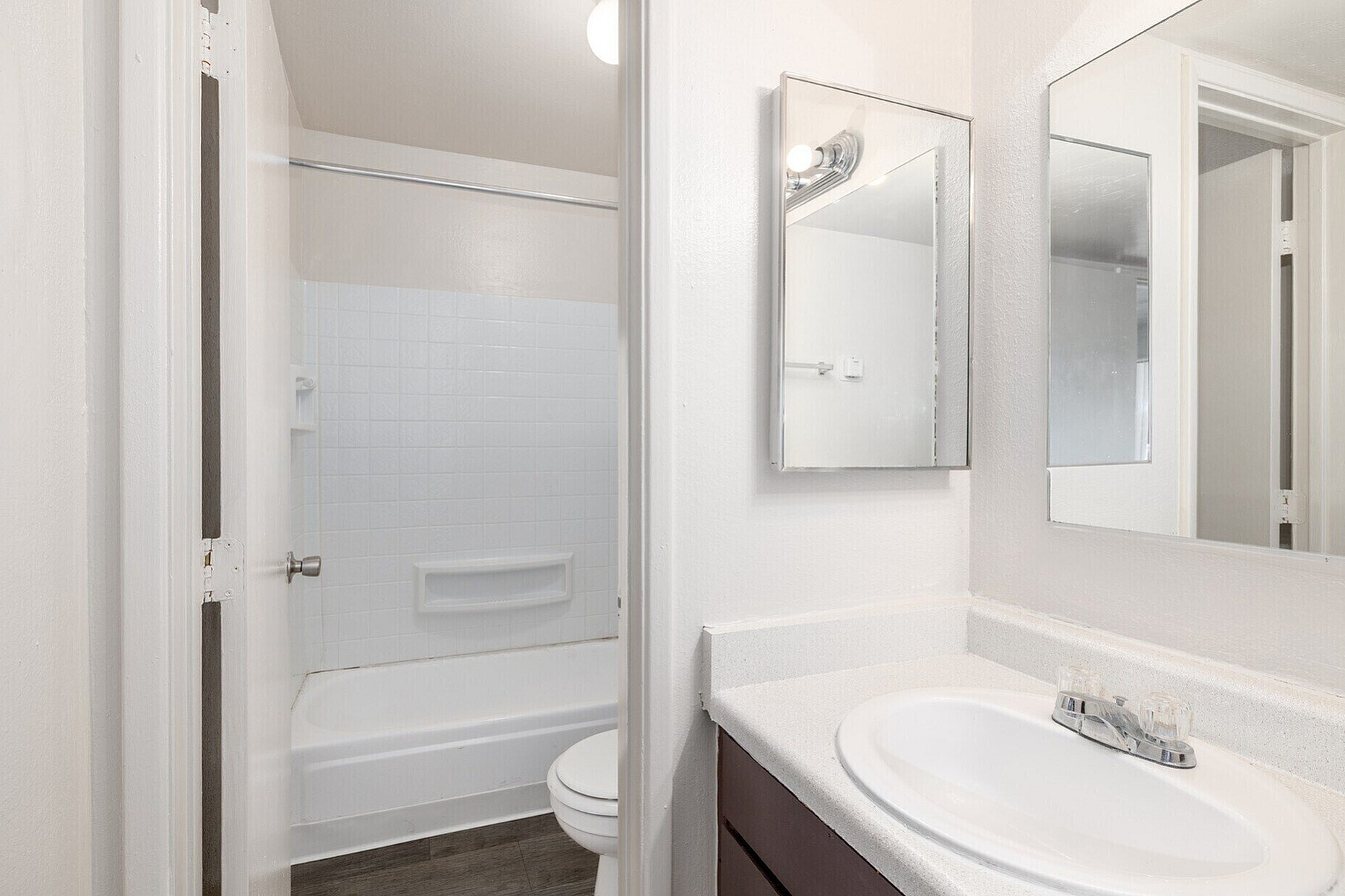Bright and modern bathroom featuring a sleek vanity with a large mirror, inviting bathtub, and stylish lighting.