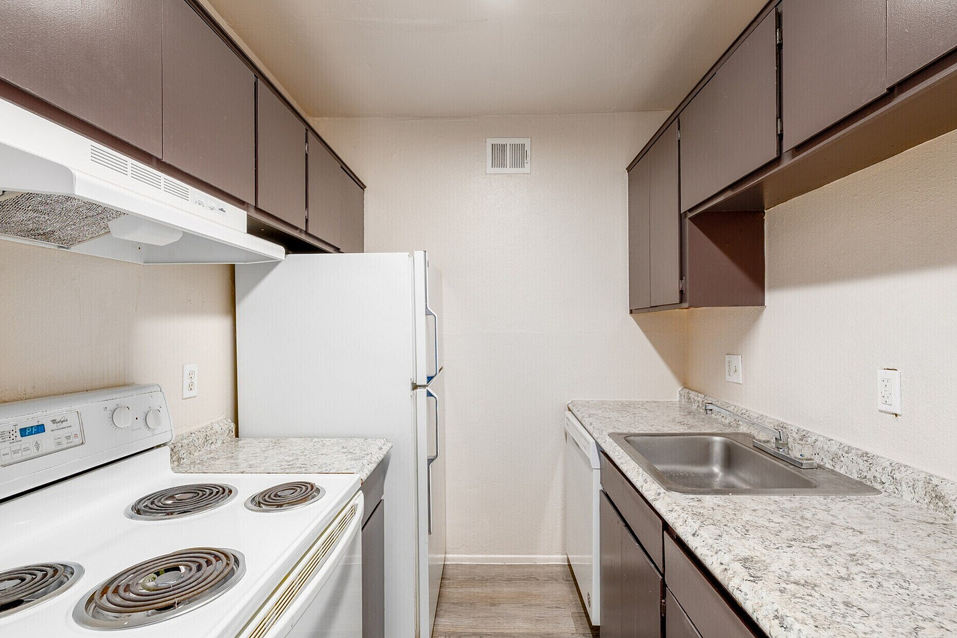 Sleek and modern galley kitchen with dark cabinetry, granite countertops, and stainless steel appliances.