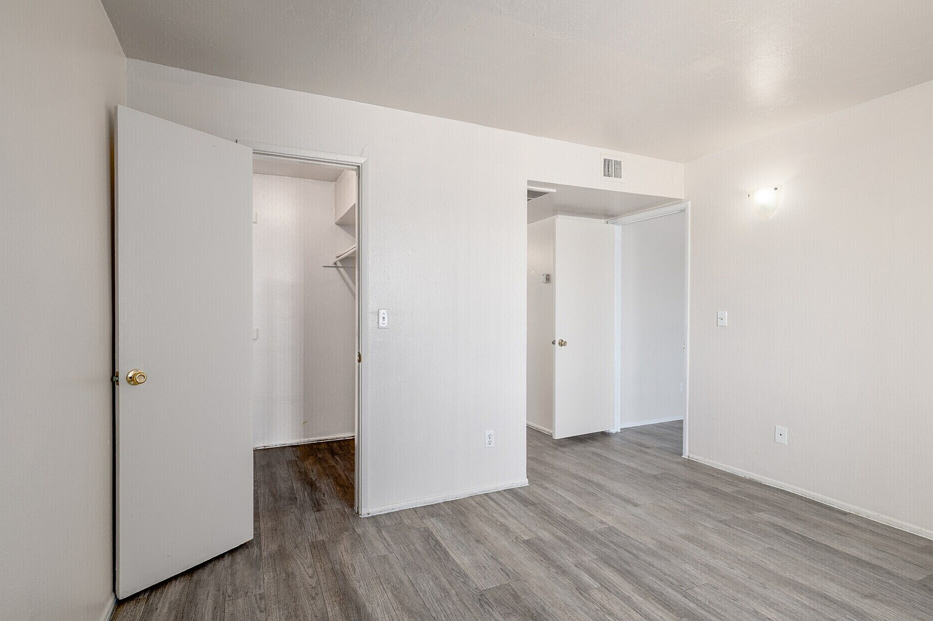 Modern apartment interior with sleek light wood flooring, ample closet space, and pristine white walls, offering a fresh and inviting atmosphere.