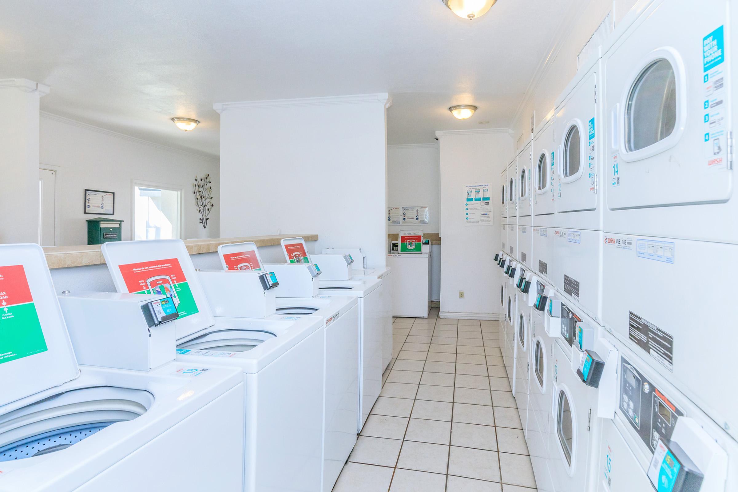 Bright and modern laundry room featuring multiple washers and dryers, offering convenience and efficiency.