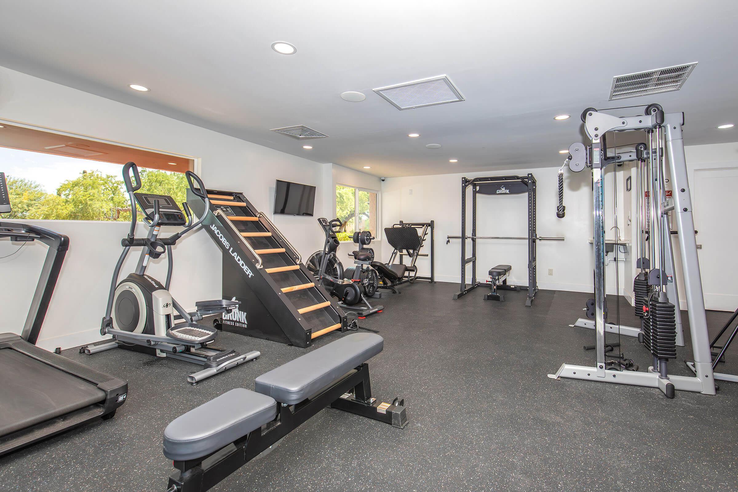 Modern fitness center with state-of-the-art equipment, including a treadmill, weight machines, and cardiovascular gear in a bright, open space.