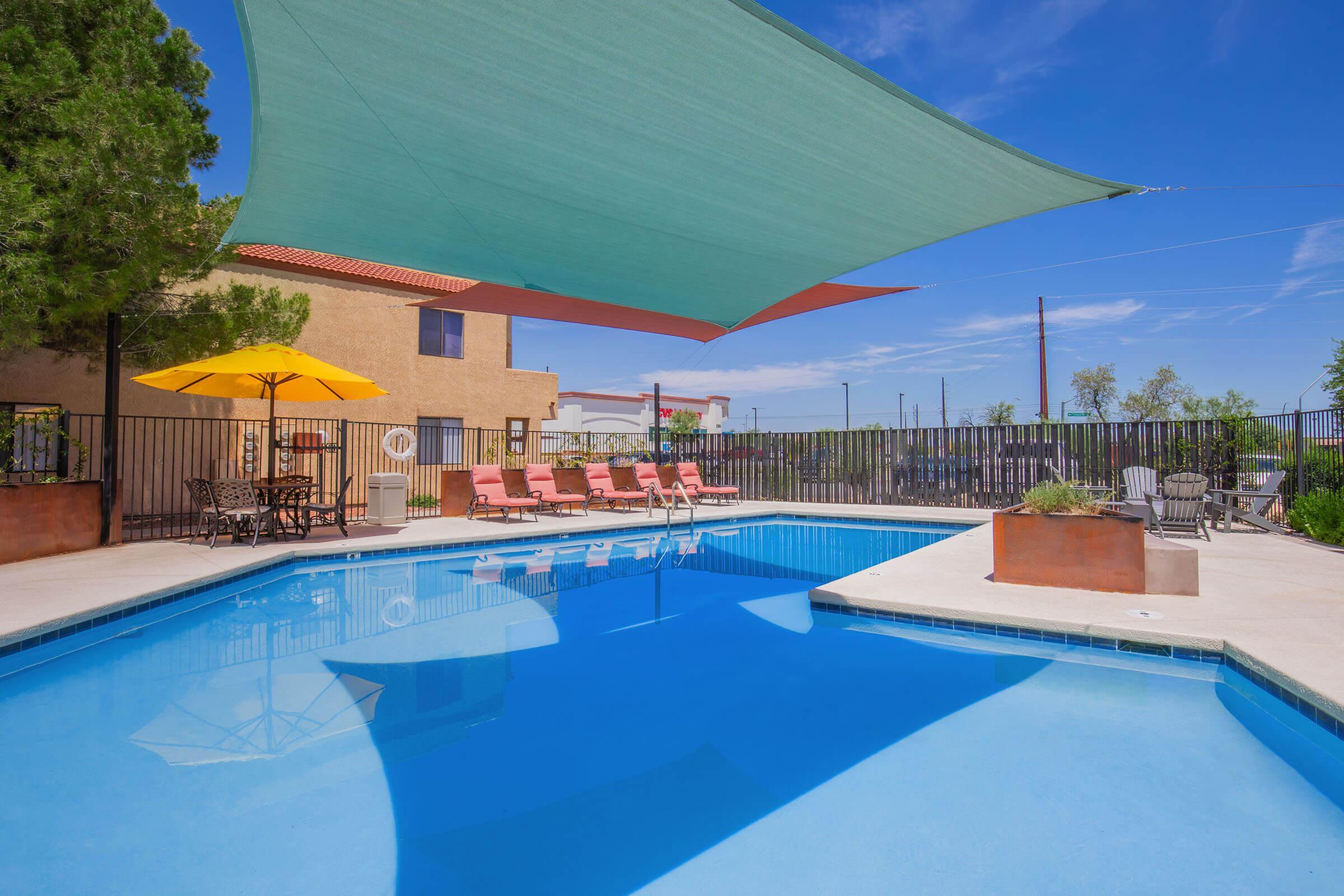 Luxurious outdoor apartment pool area with sun loungers, vibrant umbrellas, and shaded relaxation spaces, ideal for a sunny escape.