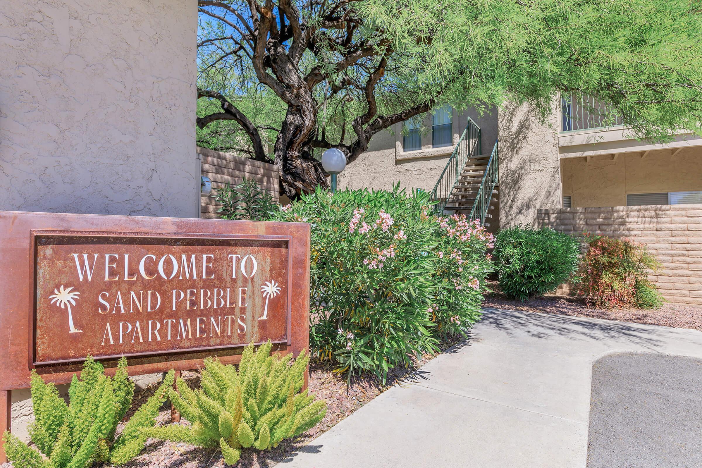 Inviting exterior of Sand Pebble Apartments surrounded by lush greenery and inviting pathways.