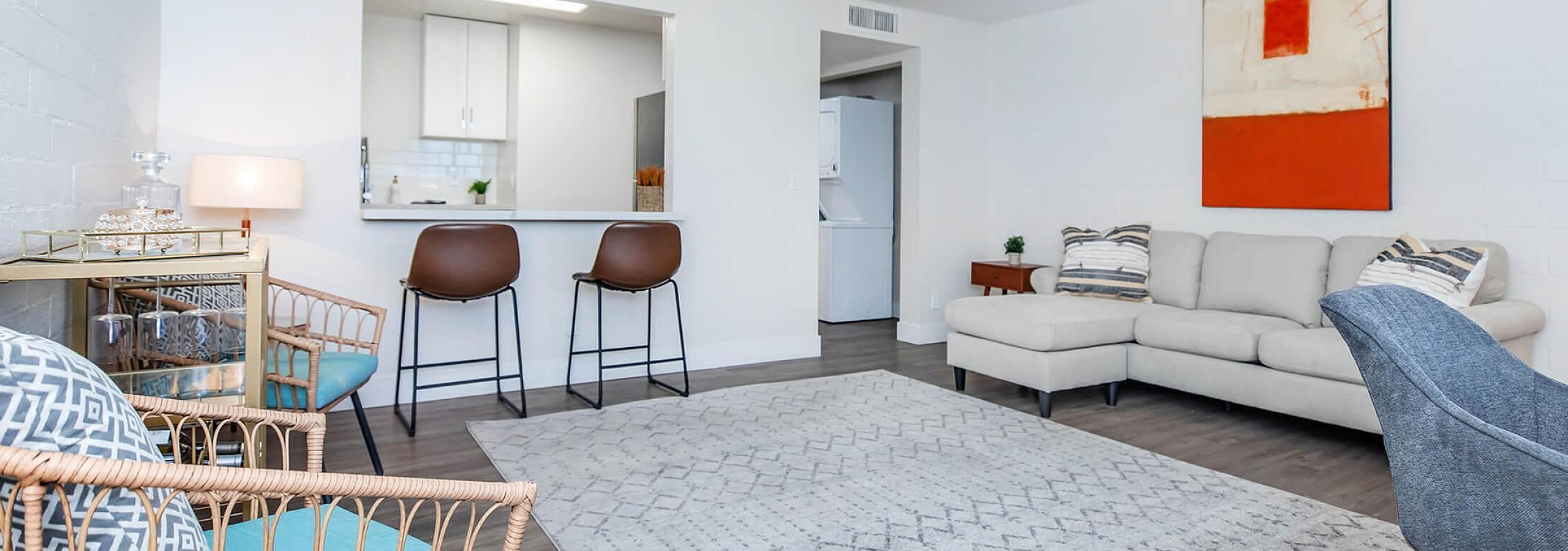 Inviting modern living room with a cozy sectional sofa, stylish accent chairs, and an open concept kitchen, perfect for relaxation and entertaining.