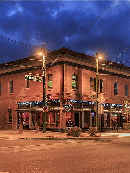 Charming historic brick building at twilight with cozy street lighting on a bustling corner in an urban setting.