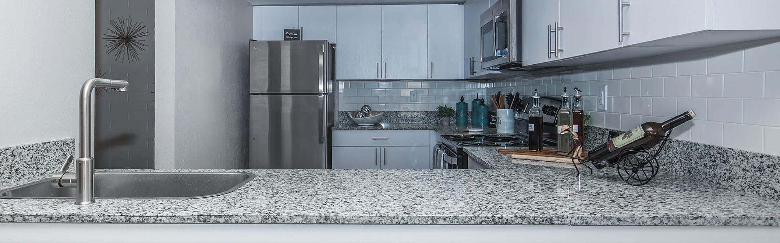 Modern kitchen with sleek granite countertops, stainless steel appliances, and elegant cabinetry, offering a stylish culinary space.