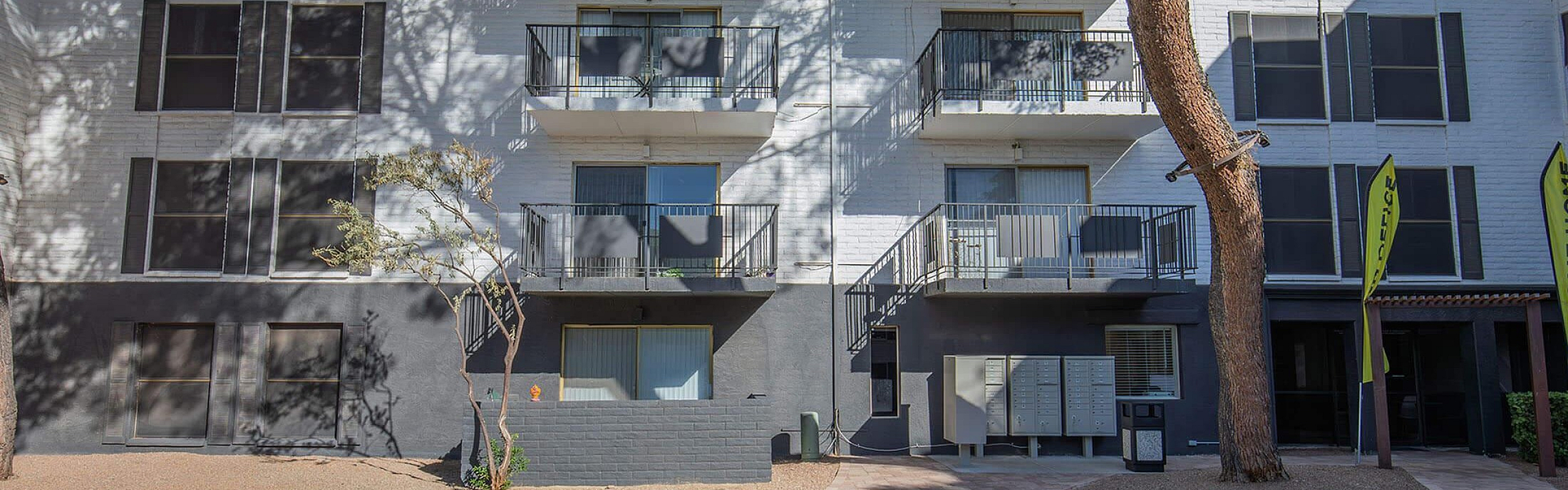 Charming apartment complex with modern balconies, abundant green space, and welcoming exterior.