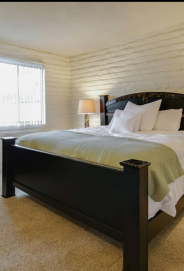 Inviting bedroom with elegant dark wood furnishings, plush carpet, and warm ambient lighting for a cozy and stylish retreat.